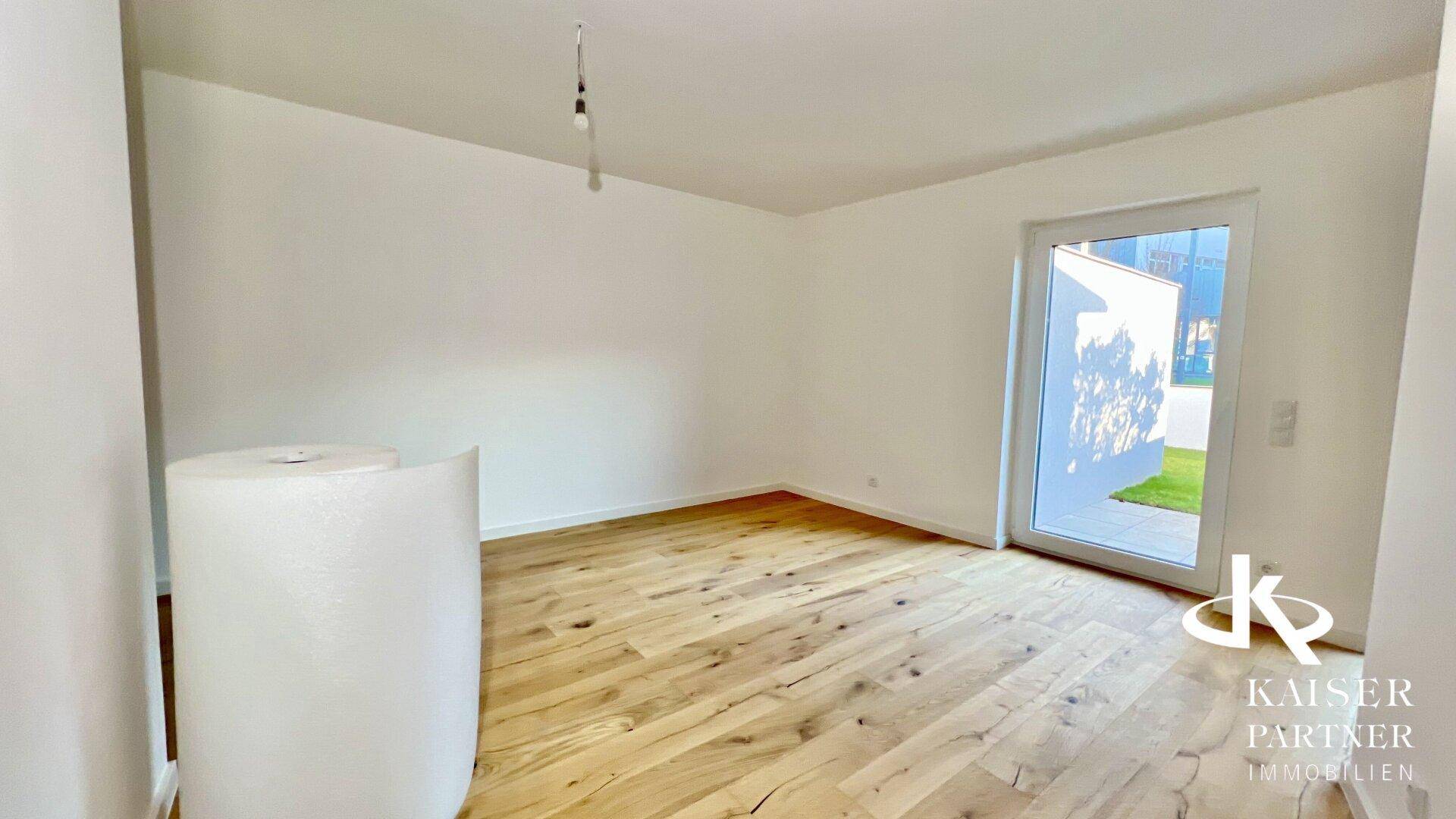 Heller Raum mit neuem Holzboden und Zugang zum Außenbereich, bereit für die Einrichtung.