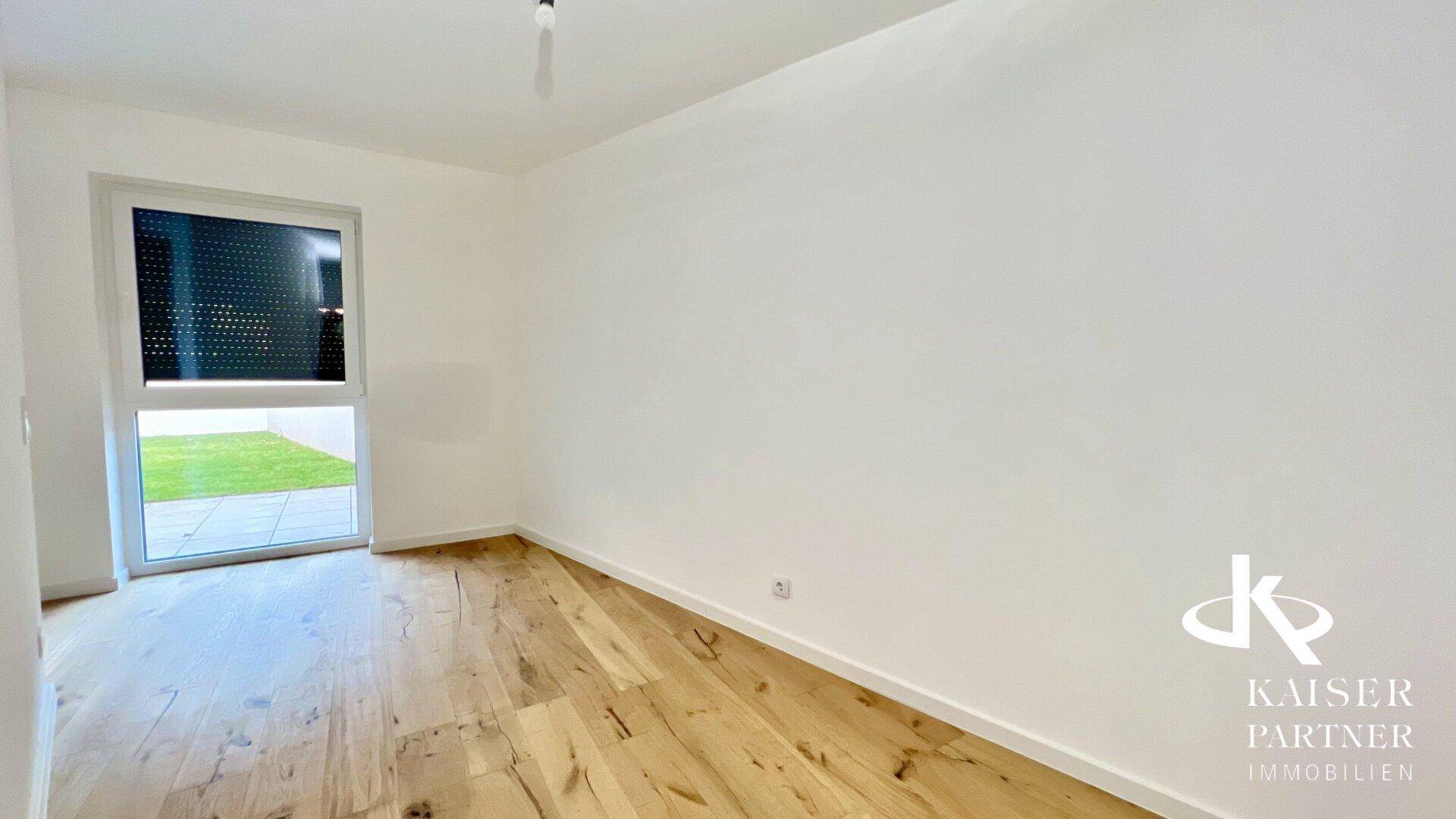 Lichtdurchfluteter Raum mit Holzboden und Blick auf den Garten, ideal als Schlafzimmer.