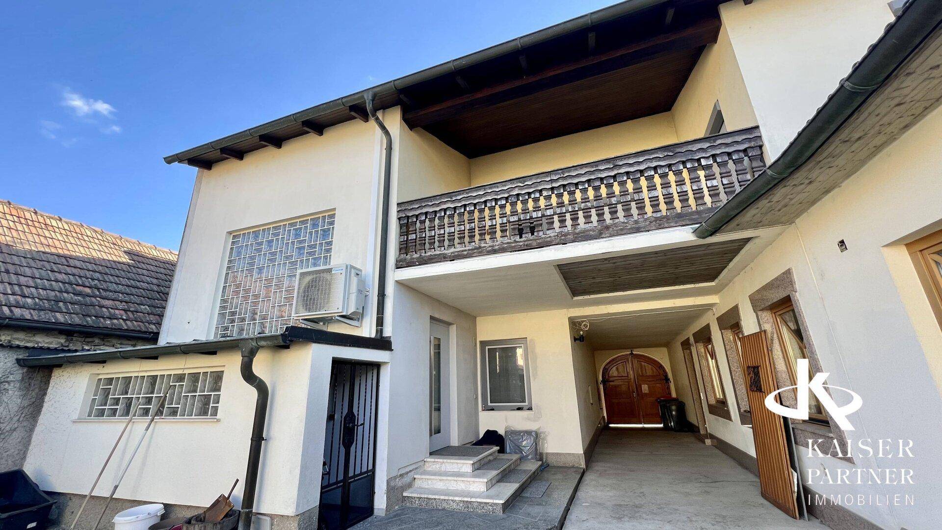 Seitenansicht des Hauses mit Balkon, überdachtem Eingangsbereich und traditionellen Holzelementen.