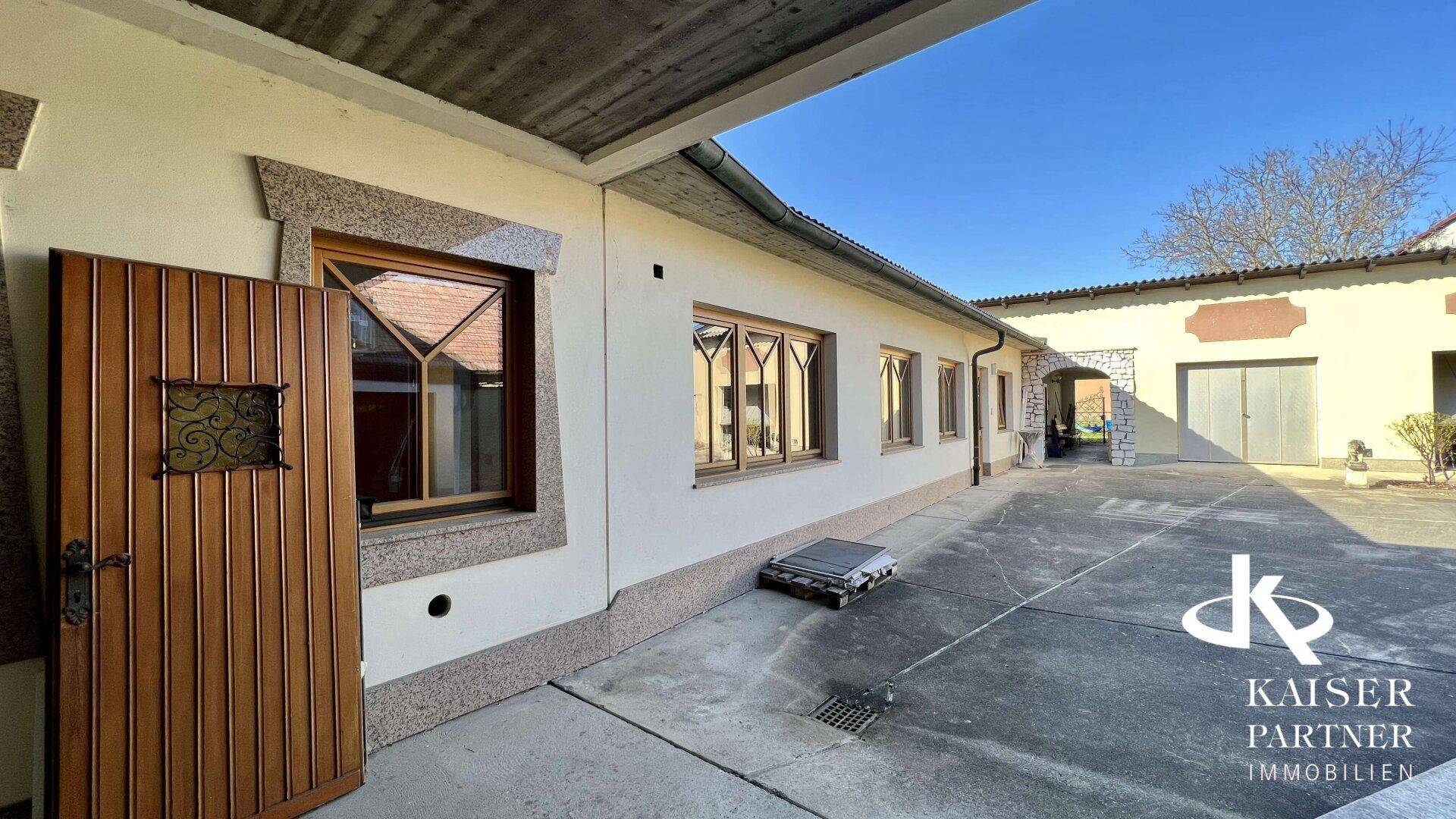 Gepflasterter Hofbereich neben dem Gebäude mit Holztür und Fenstern in traditionellem Stil.