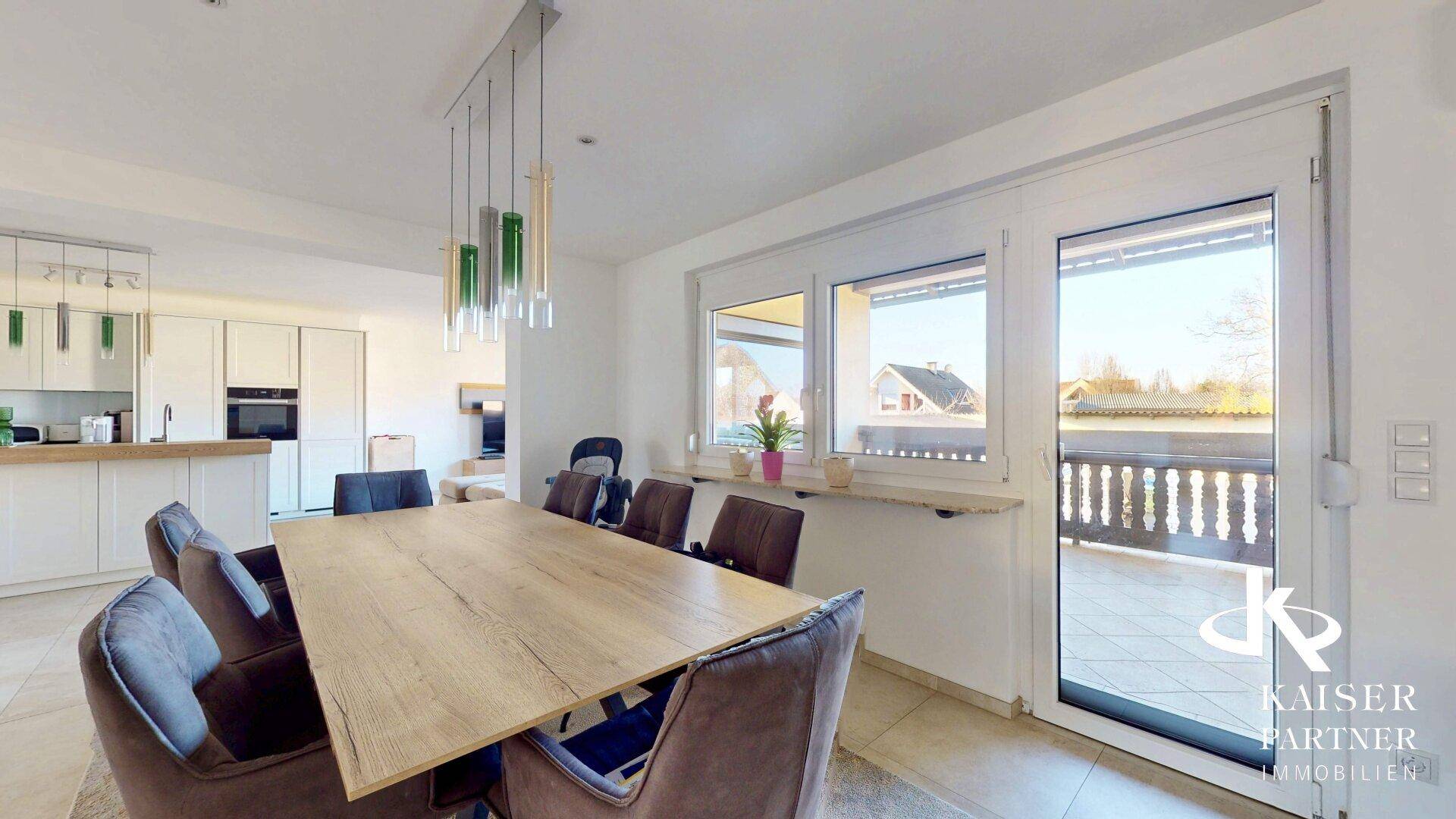 Essbereich mit großem Holztisch, modernen Stühlen und Blick auf den Balkon.