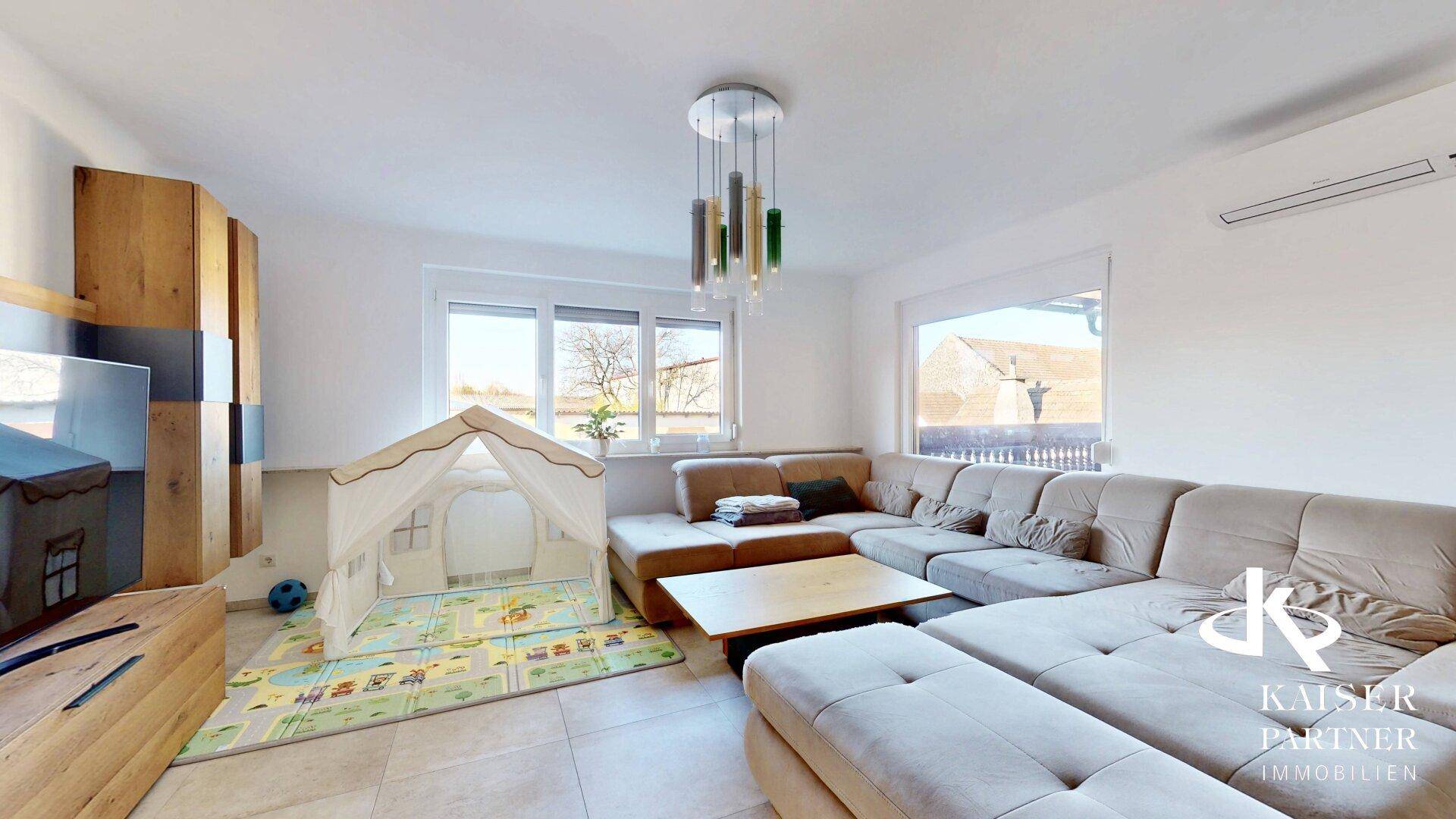 Gemütliches Wohnzimmer mit großem Ecksofa, Kinderspielbereich und viel Tageslicht.