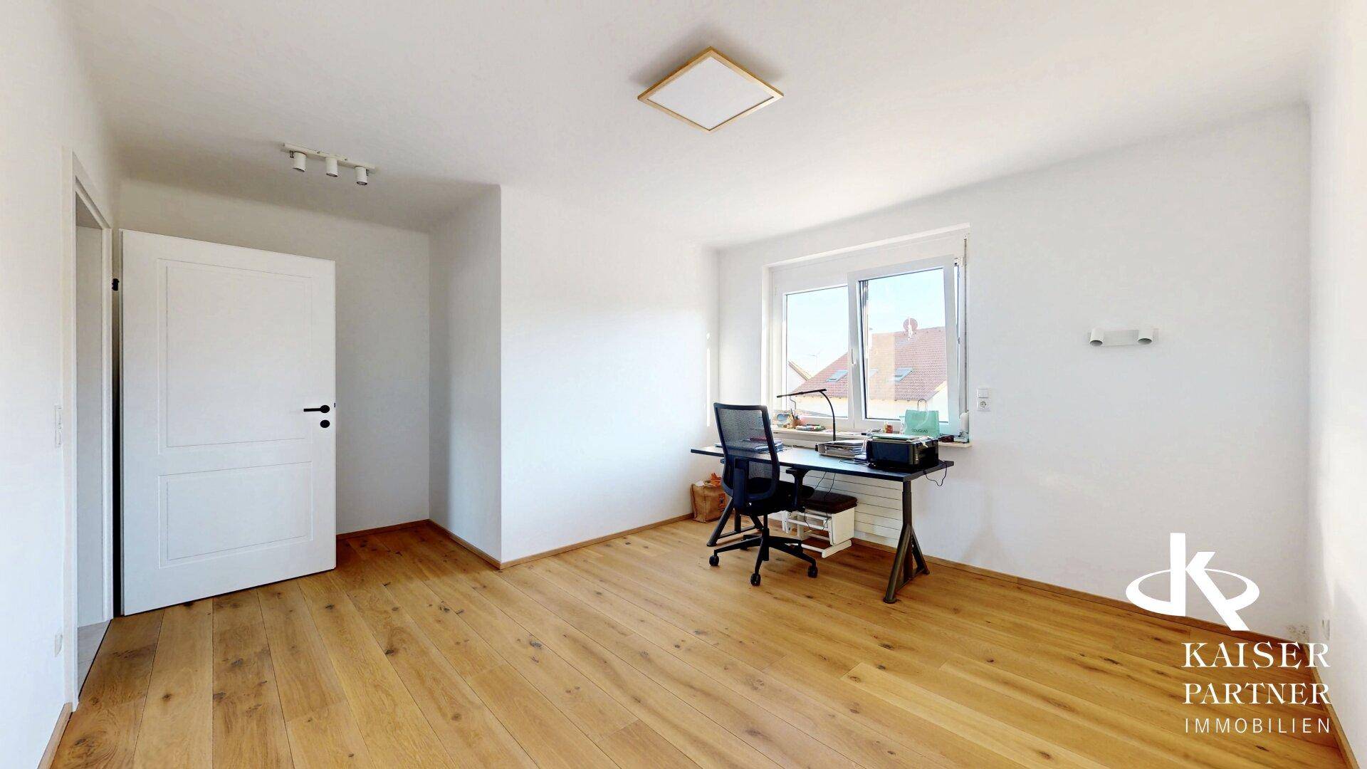 Ruhiges Arbeitszimmer mit Holzboden, Schreibtisch und Fenster für natürliches Licht.