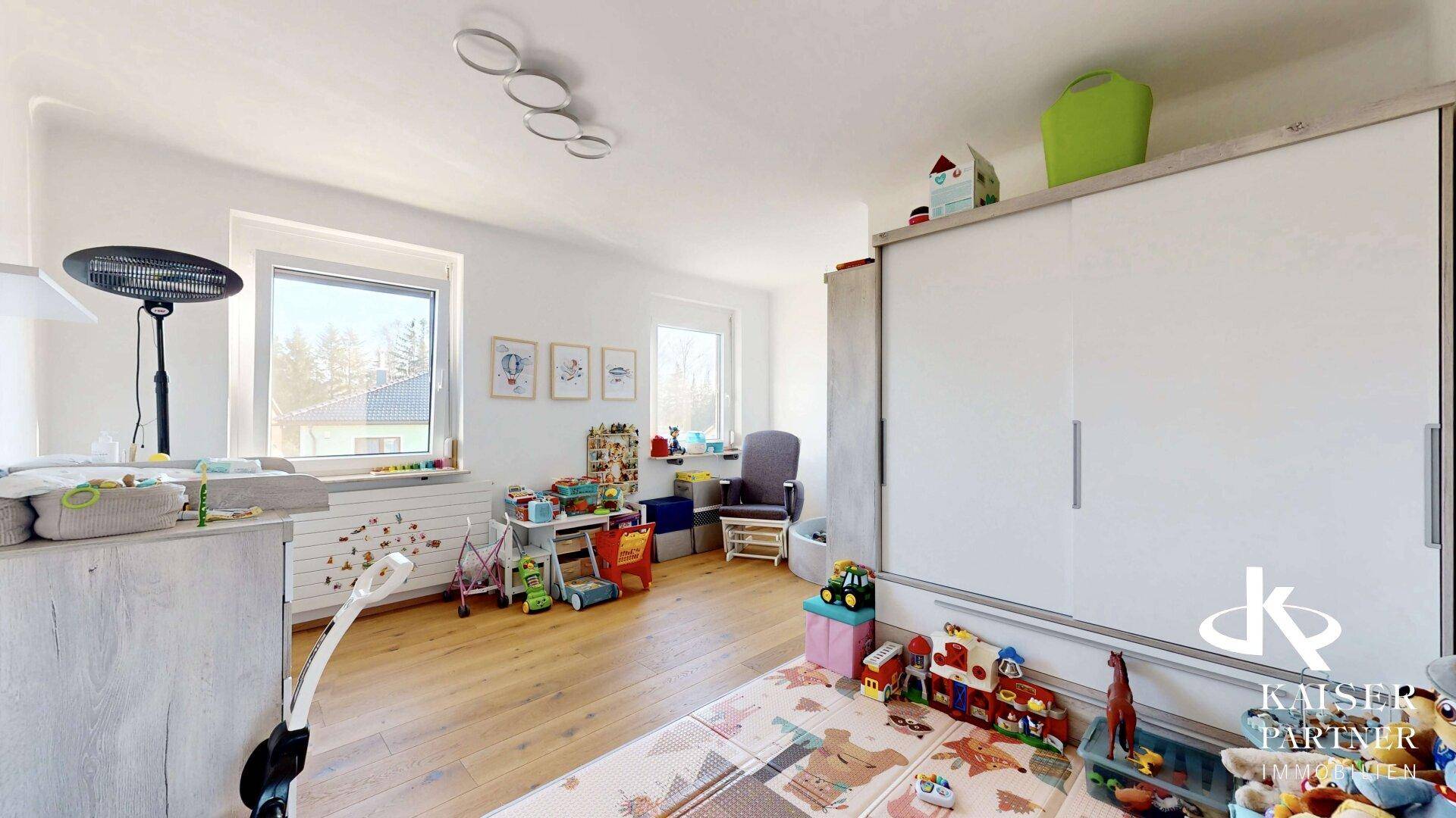 Kinderzimmer mit Spielbereich, Schrank und hellem Holzboden.
