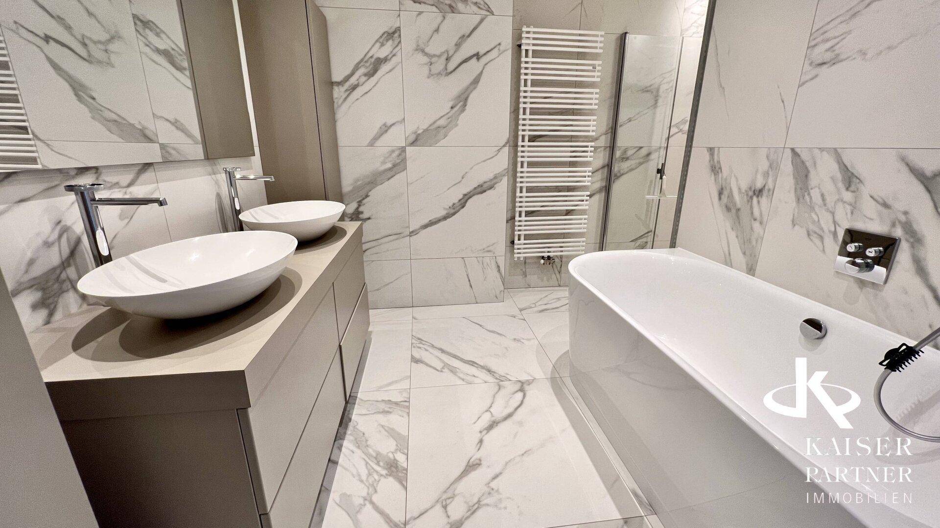 Modernes Badezimmer mit freistehender Badewanne, Doppelwaschbecken und Marmorfliesen.
