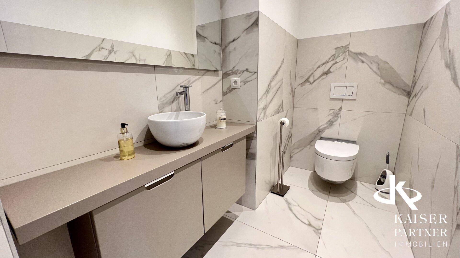 Stilvolles Gäste-WC mit Wand-WC, Einzelwaschbecken und Marmorfliesen.
