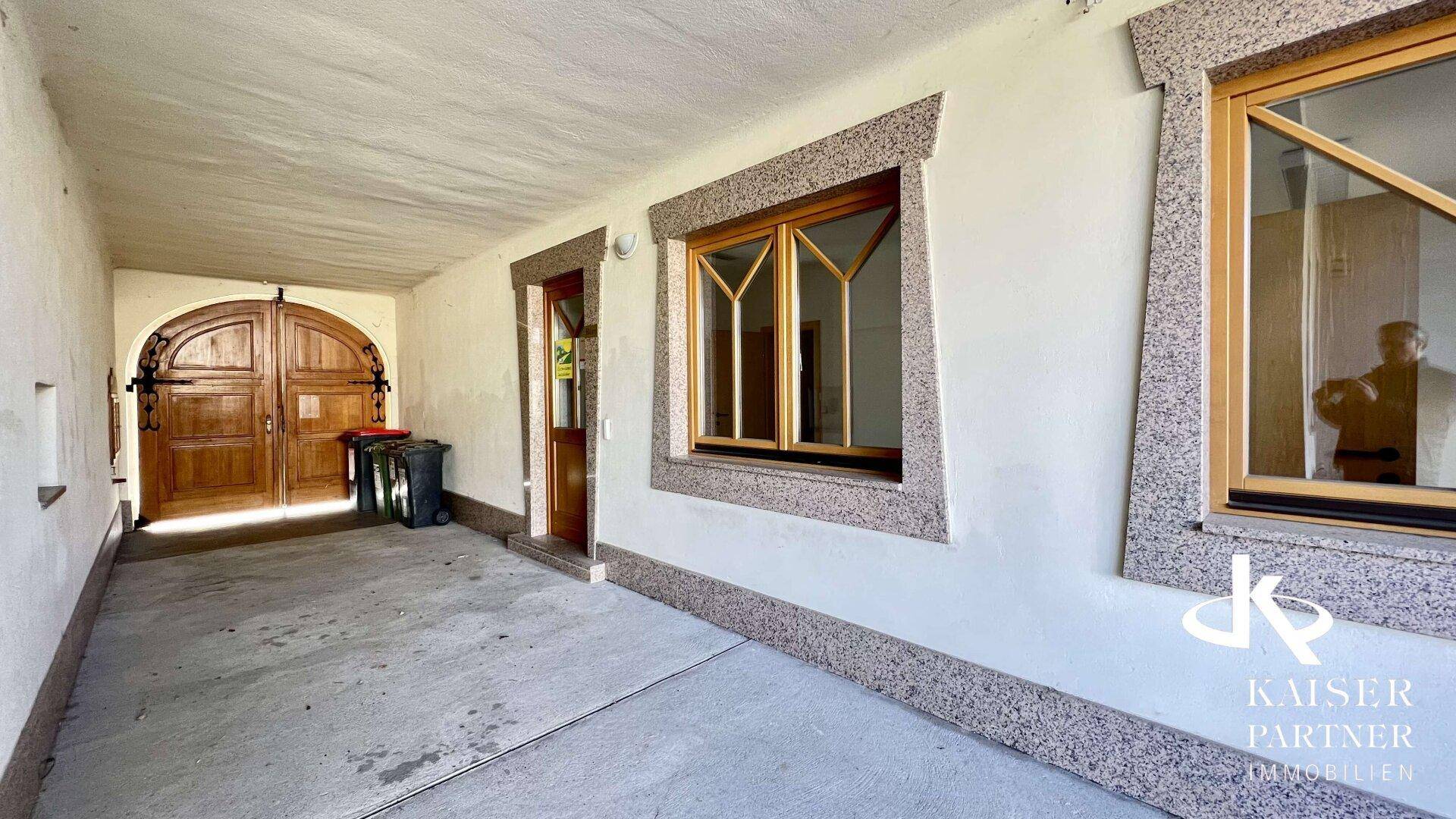 Überdachter Eingangsbereich mit Holztüren und Zugang zum Gebäude.