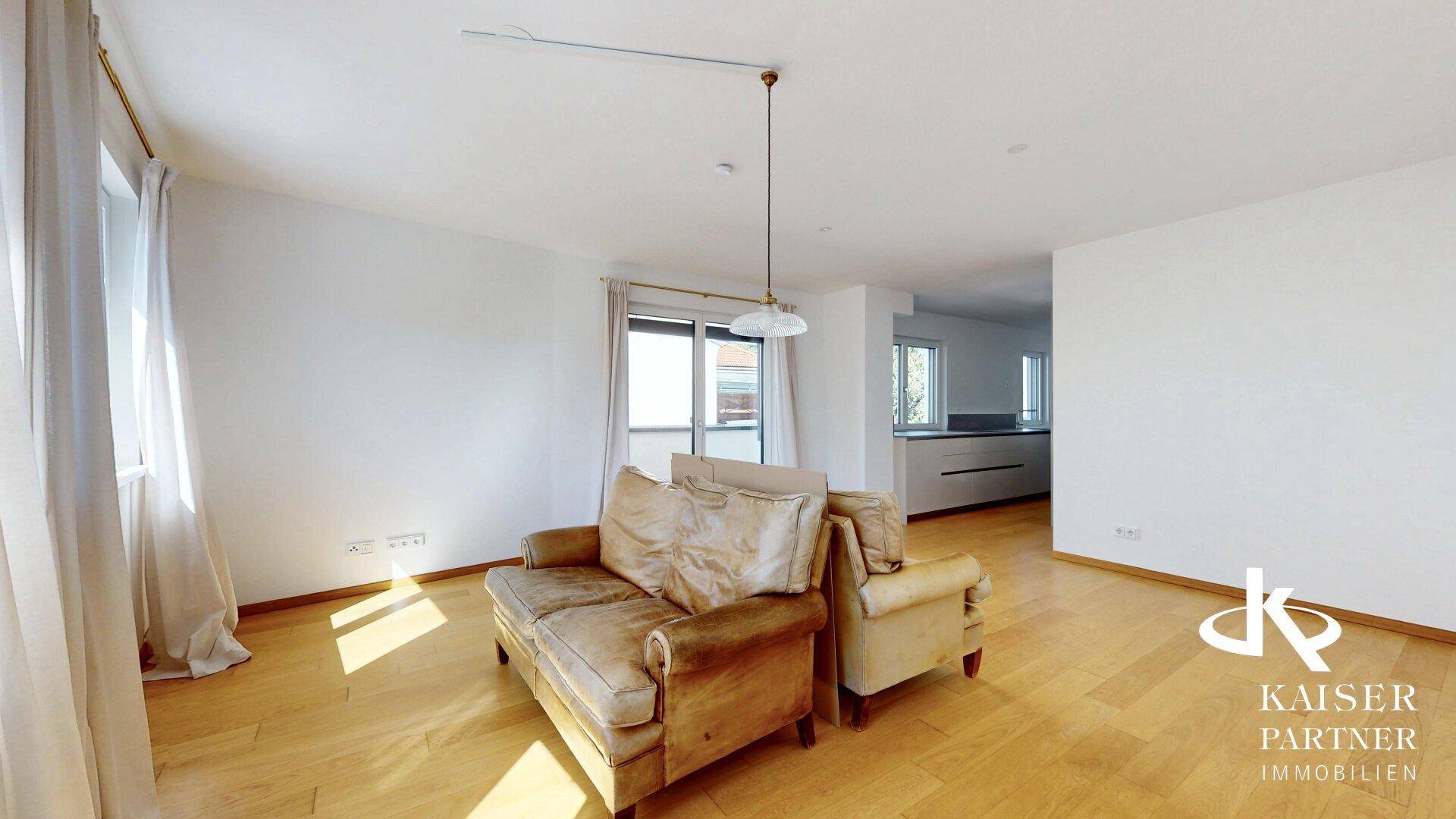 Geräumiges Wohnzimmer mit hellem Holzfußboden und offener Verbindung zur Küche, ideal für modernes Wohnen.