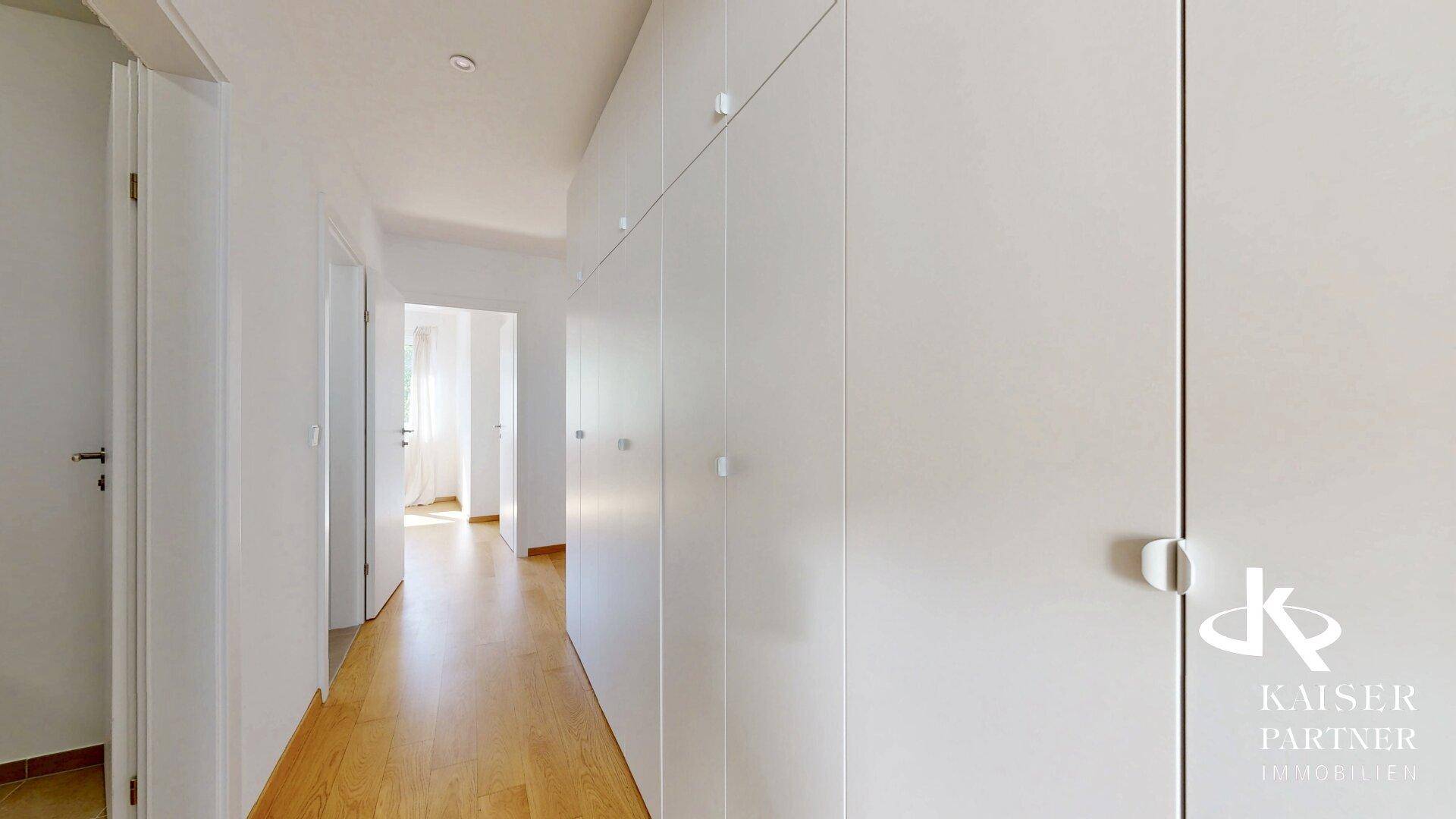 Langer, heller Flur mit Einbauschränken, der zu den verschiedenen Wohnbereichen der Wohnung führt.