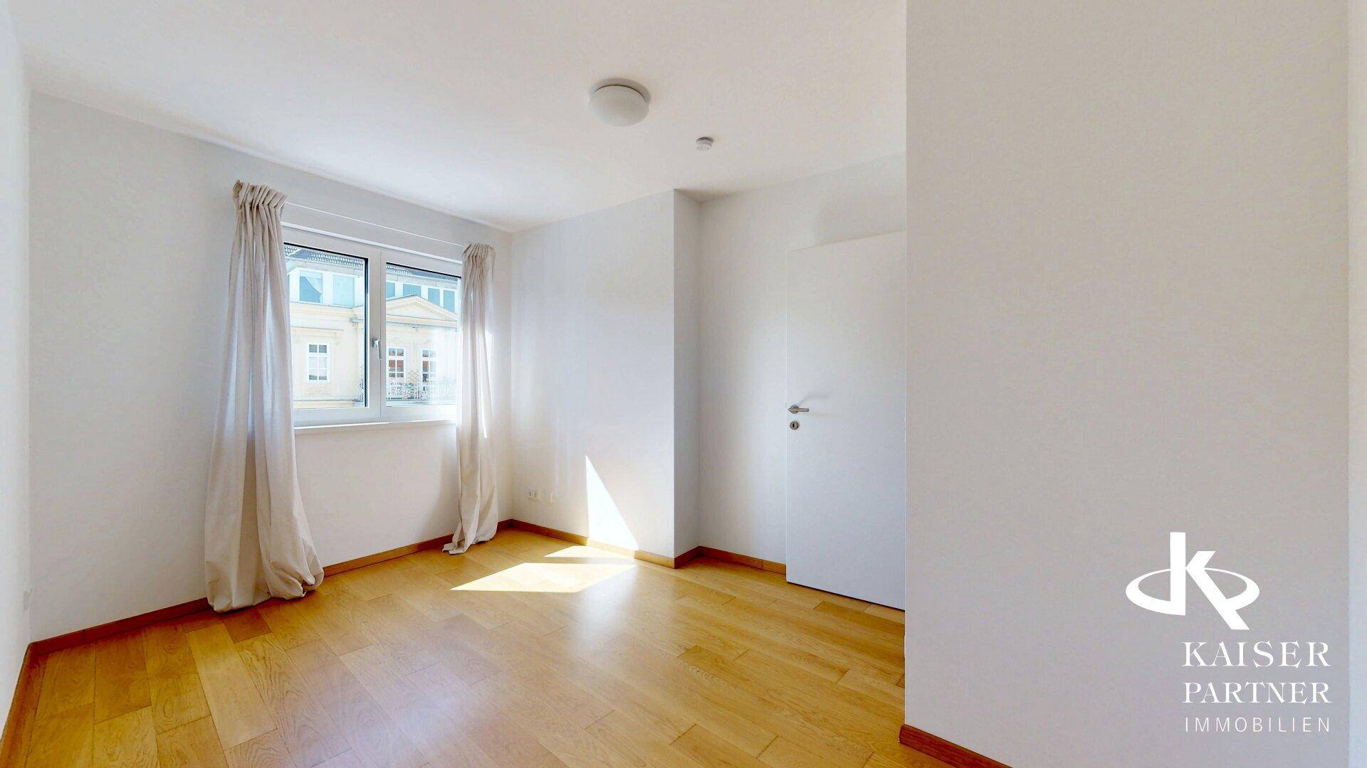 Sonniger Raum mit Holzparkettboden und Blick auf die Umgebung, ideal als Schlaf- oder Arbeitszimmer.