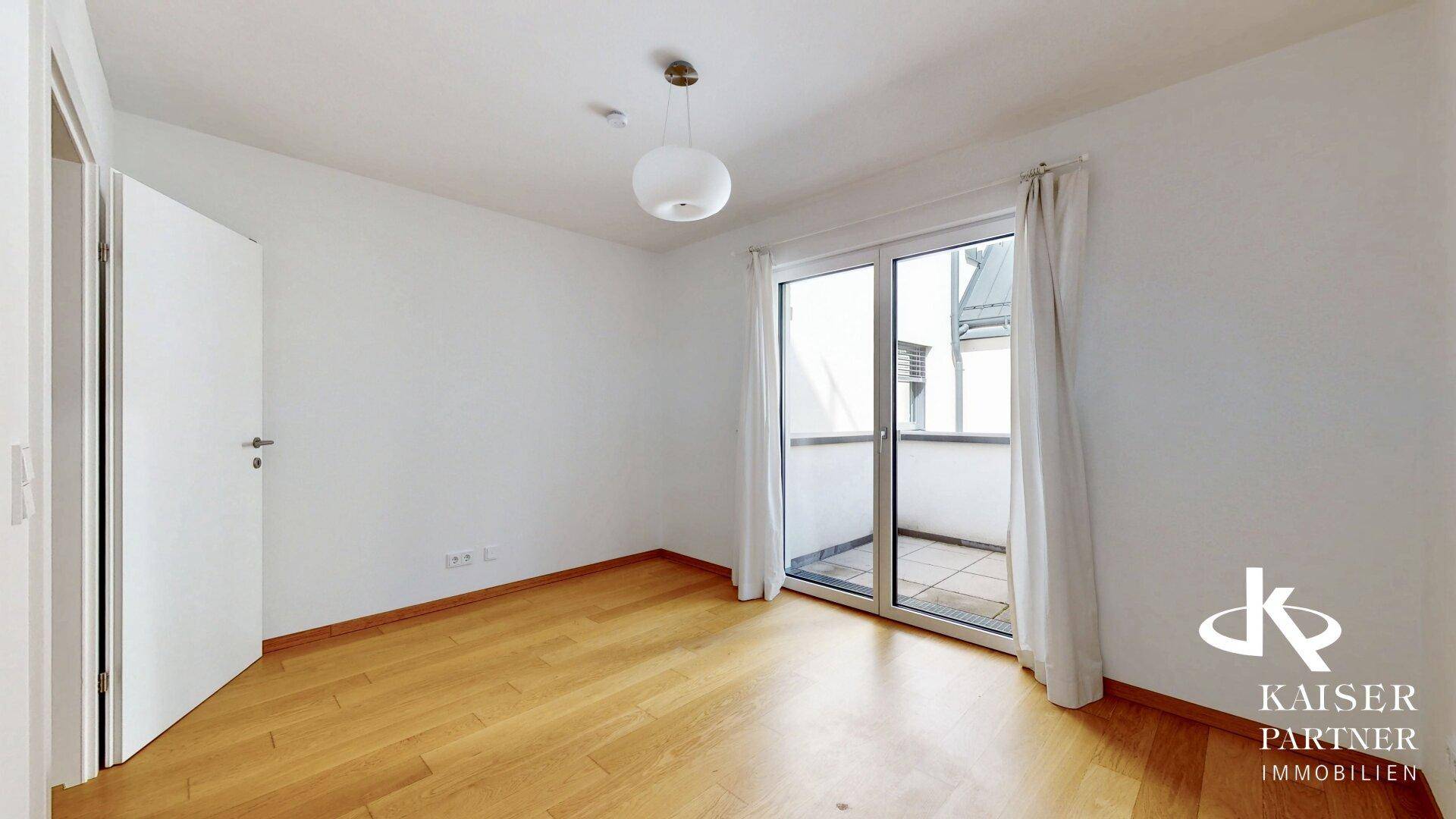 Helles Schlafzimmer mit Holzparkettboden und direktem Zugang zum Balkon, ideal für frische Luft.