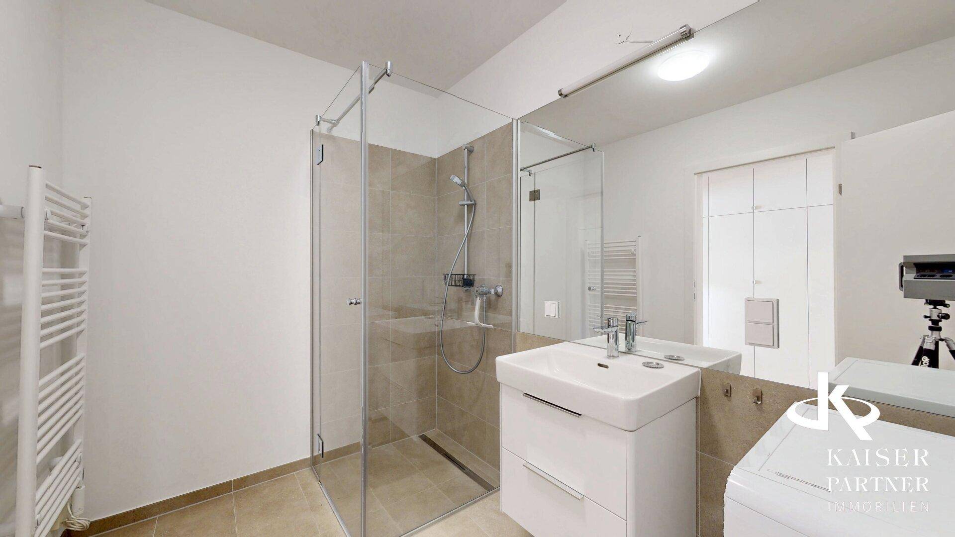 Modernes Badezimmer mit begehbarer Dusche, Waschbecken und beheiztem Handtuchhalter.