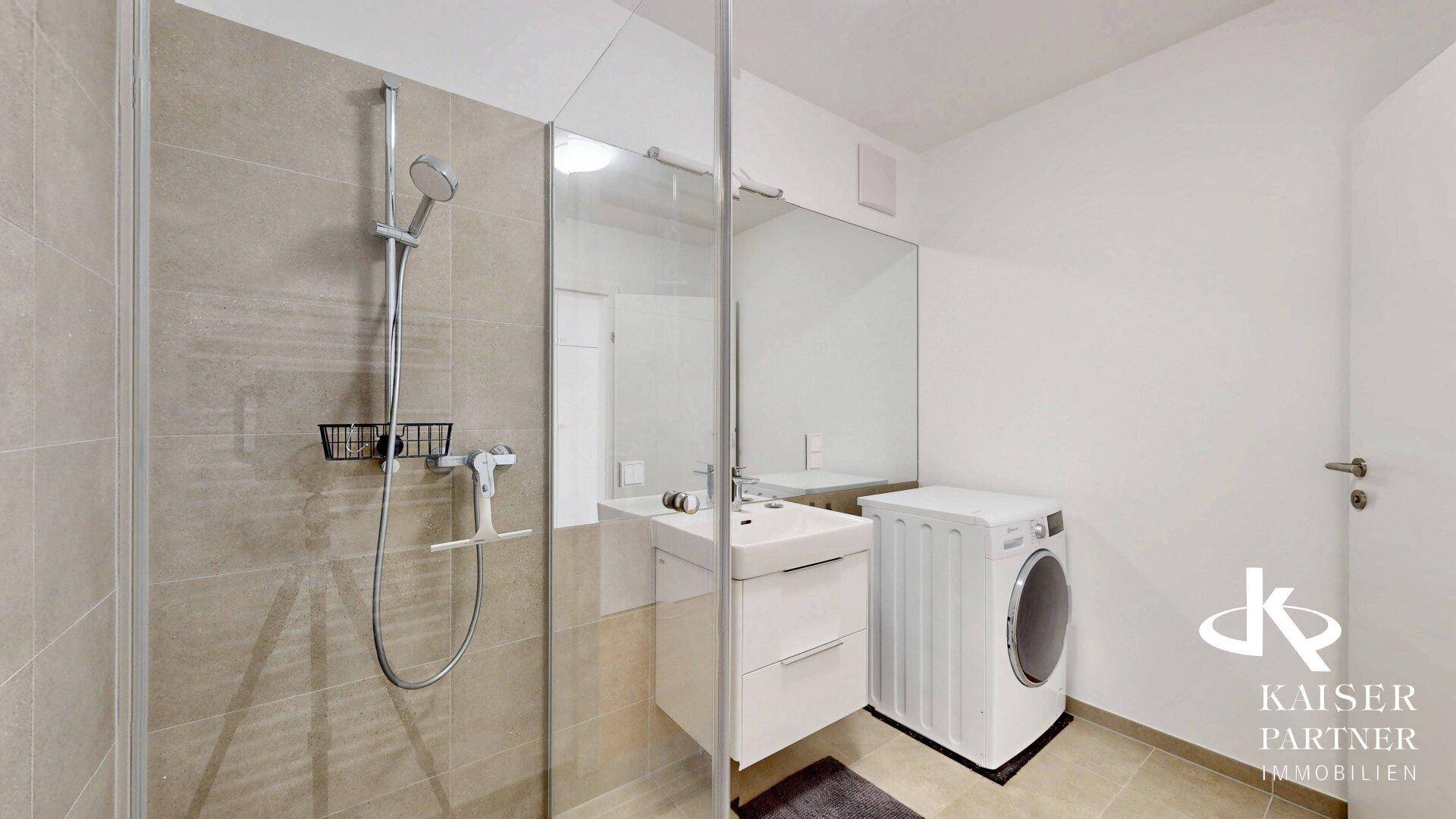Helles Badezimmer mit moderner Dusche, Waschbecken und Waschmaschine, praktisch und funktional gestaltet.
