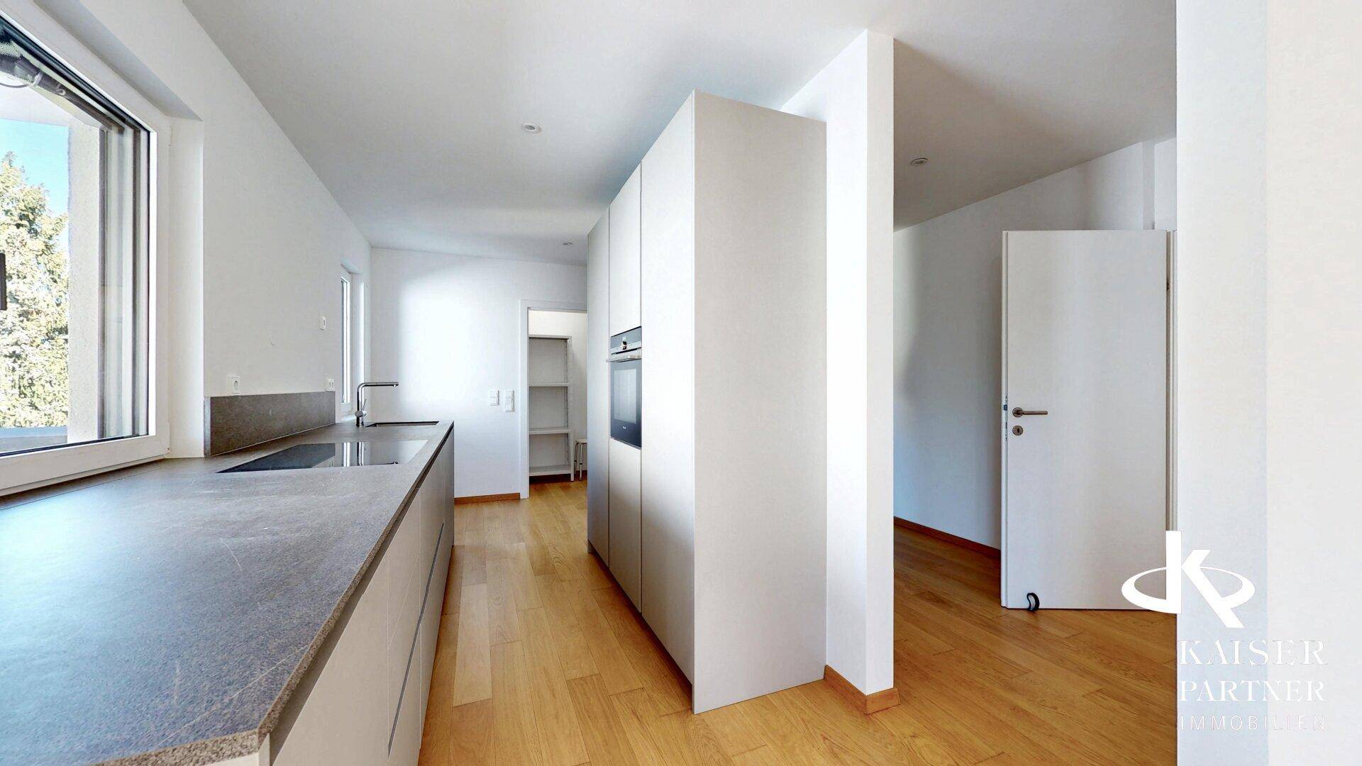 Moderne Einbauküche mit integriertem Backofen und viel Stauraum, verbunden mit einem hellen Flur.