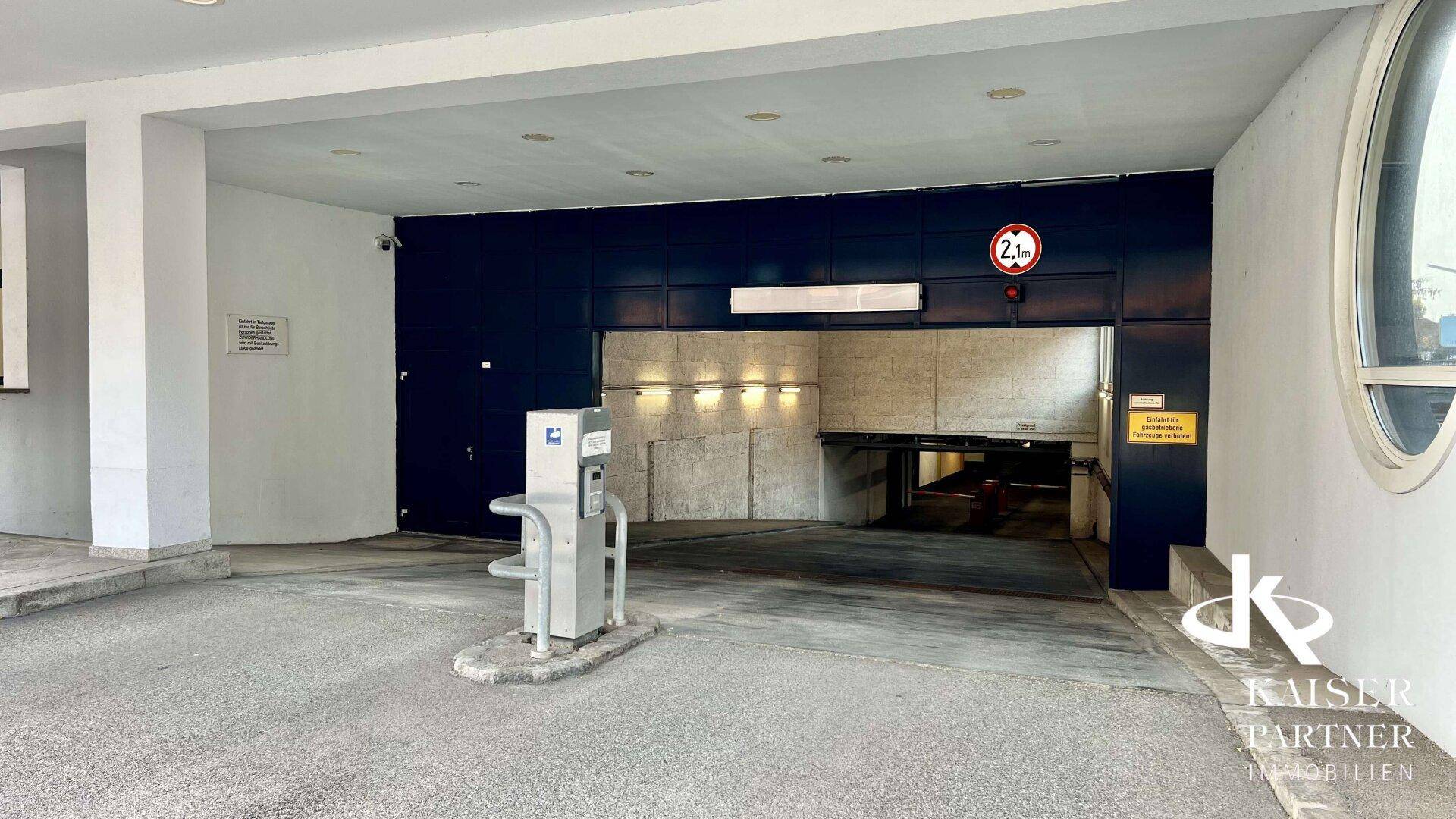 Einfahrt zur Tiefgarage mit Höhenbegrenzung und Zugangskontrolle.