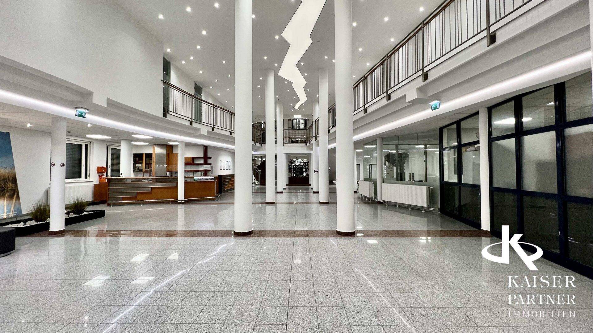 Geräumige, helle Lobby mit hohen Säulen, glänzendem Fliesenboden und moderner Beleuchtung.