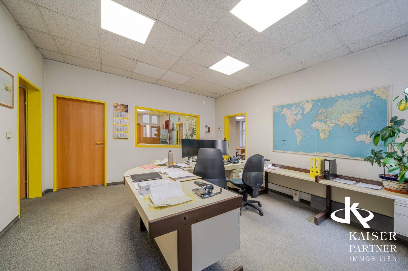 Privates Büro mit Schreibtisch, Bürostuhl und einer Weltkarte an der Wand.