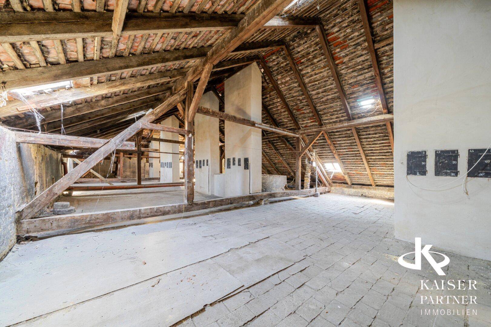 Geräumiger Dachboden mit sichtbarer Holzbalkenkonstruktion und Ziegeldach, bereit für den Ausbau.