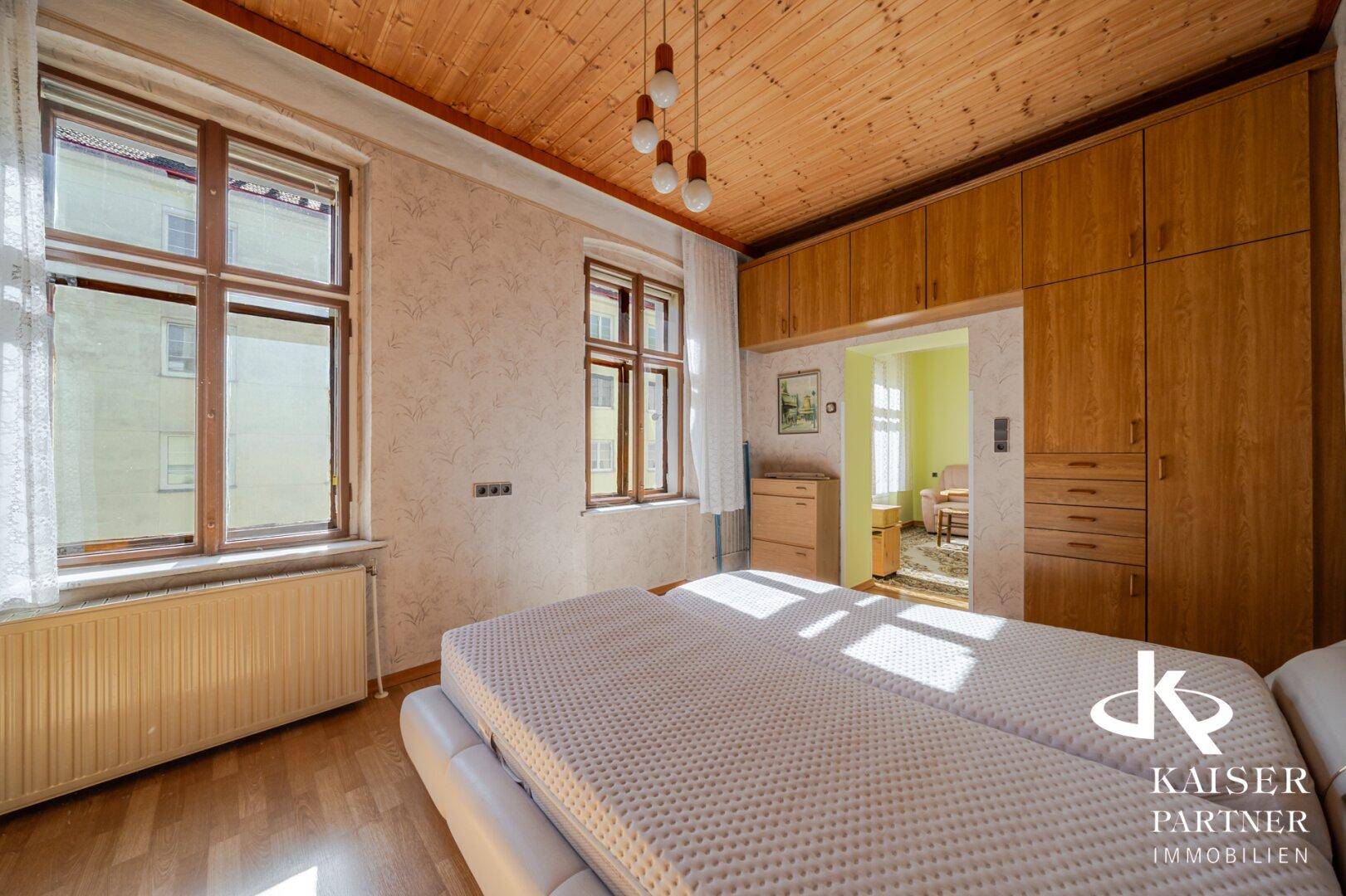 Schlafzimmer mit Holzdecke, Einbauschränken und hellem Holzboden.
