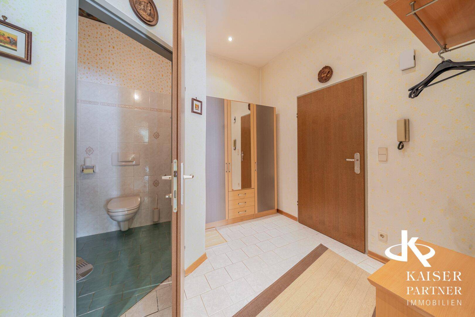 Flur mit Fliesenboden und Blick in ein separates WC.
