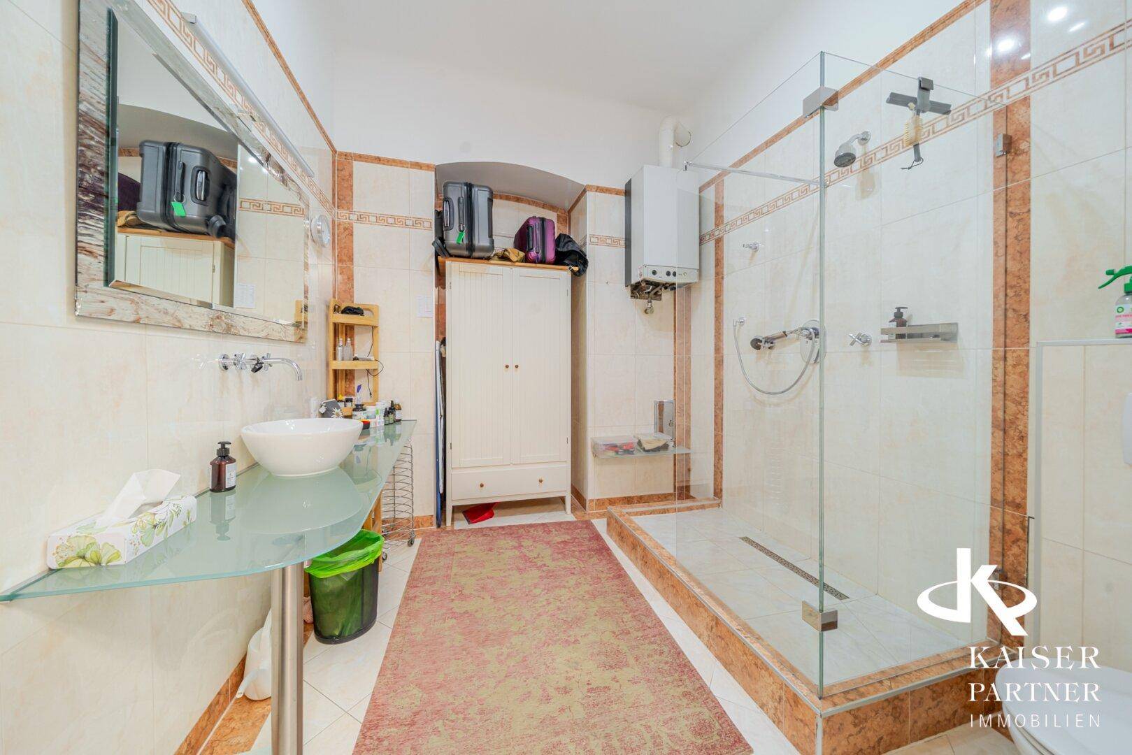 Badezimmer mit Fliesen, begehbarer Dusche und modernem Waschbecken.