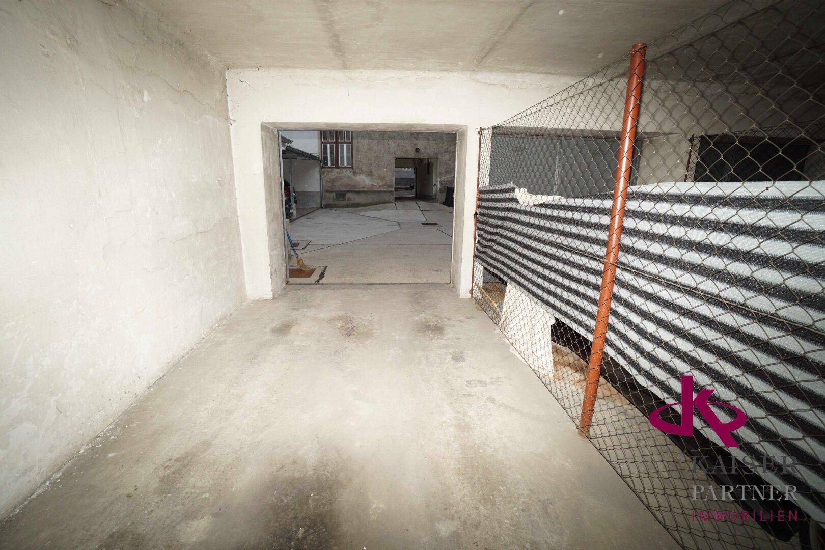 Garageninnenraum mit Blick auf einen hinteren Ausgang, der zu einem Außenbereich führt.