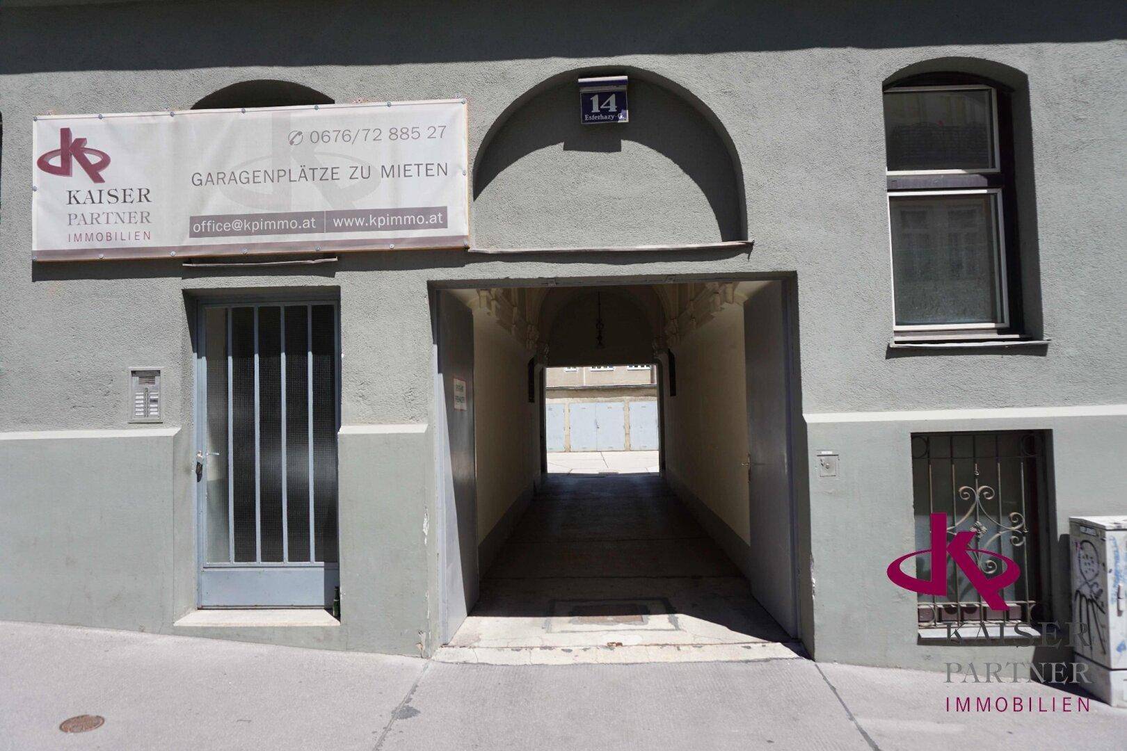 Gebäudeeingang mit Torbogen und einem Schild, das Garagenplätze zur Miete anbietet.