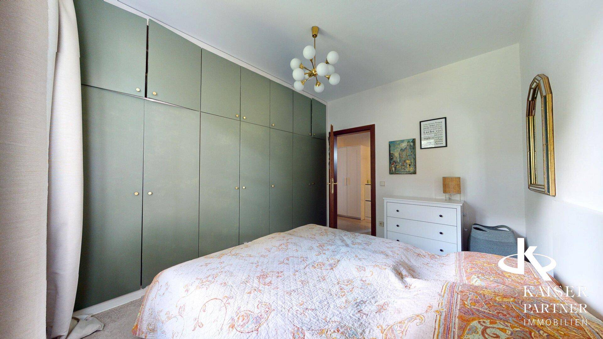 Schlafzimmer mit Einbauschränken, Kommode und hellem Teppichboden.
