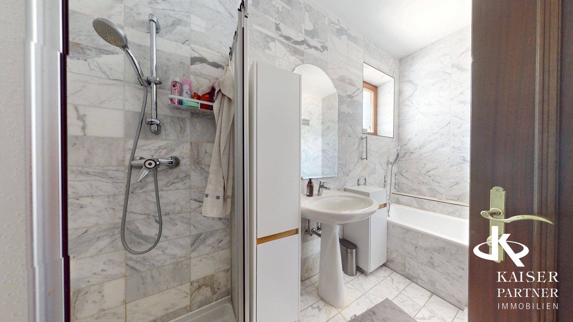 Modernes Badezimmer mit Marmorfliesen, Dusche und Badewanne.