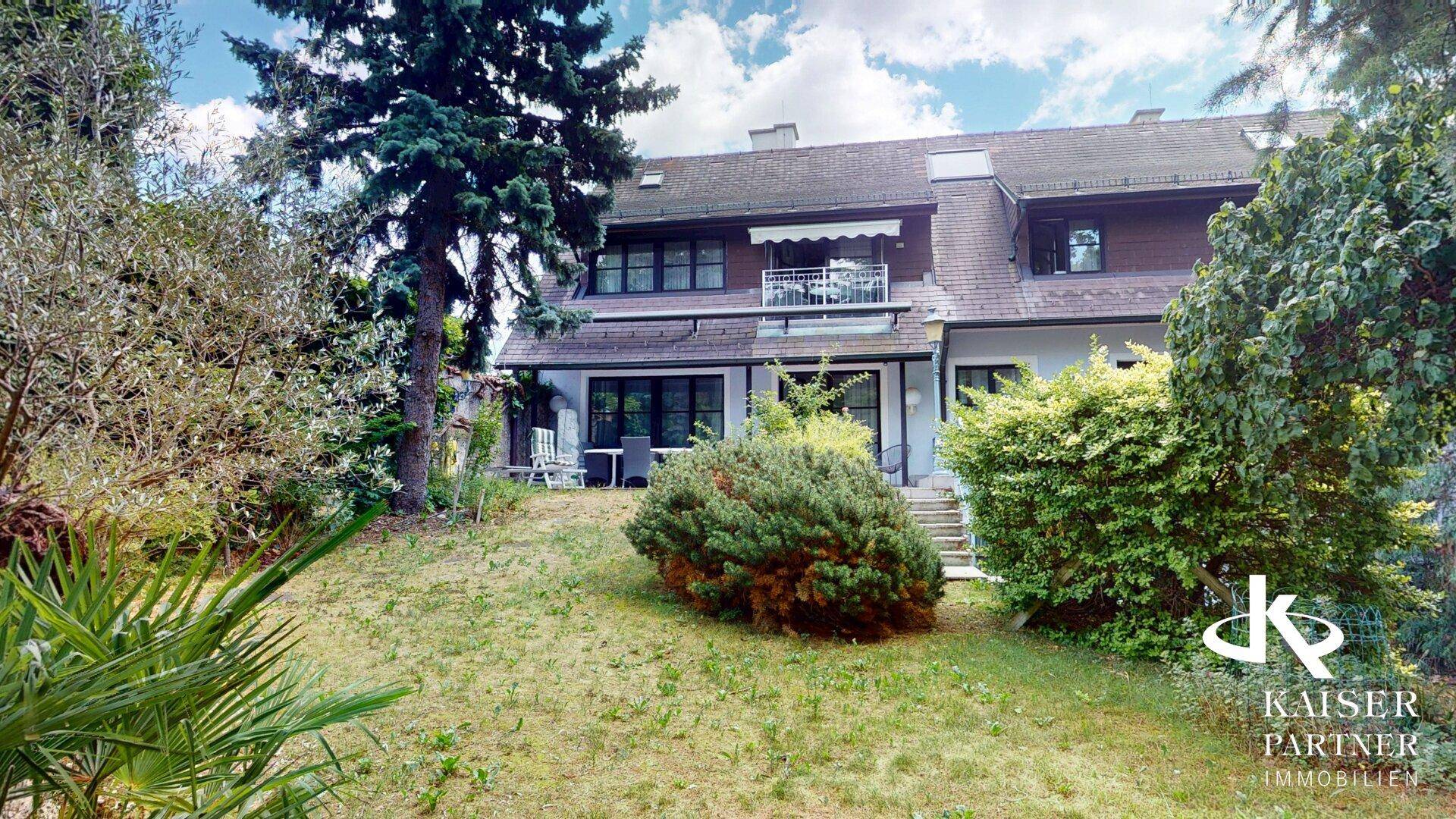 Rückansicht des Hauses mit Garten, Terrasse und Balkonen, umgeben von viel Grün.