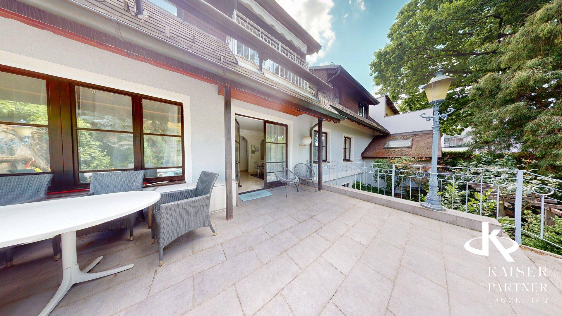Große Terrasse mit Sitzgelegenheiten und Blick auf das grüne Grundstück.