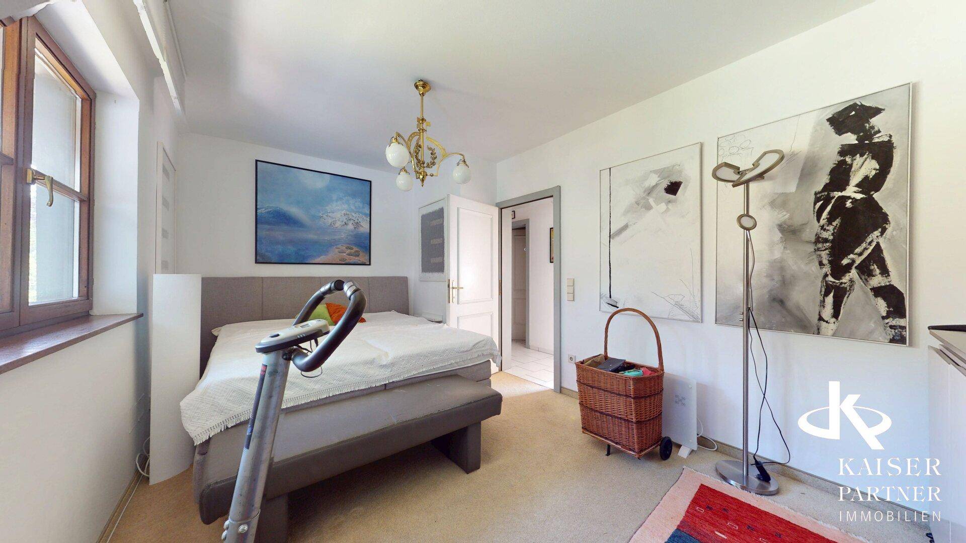 Schlafzimmer im Dachgeschoss mit Doppelbett, Kunstwerken und Fitnessgerät.