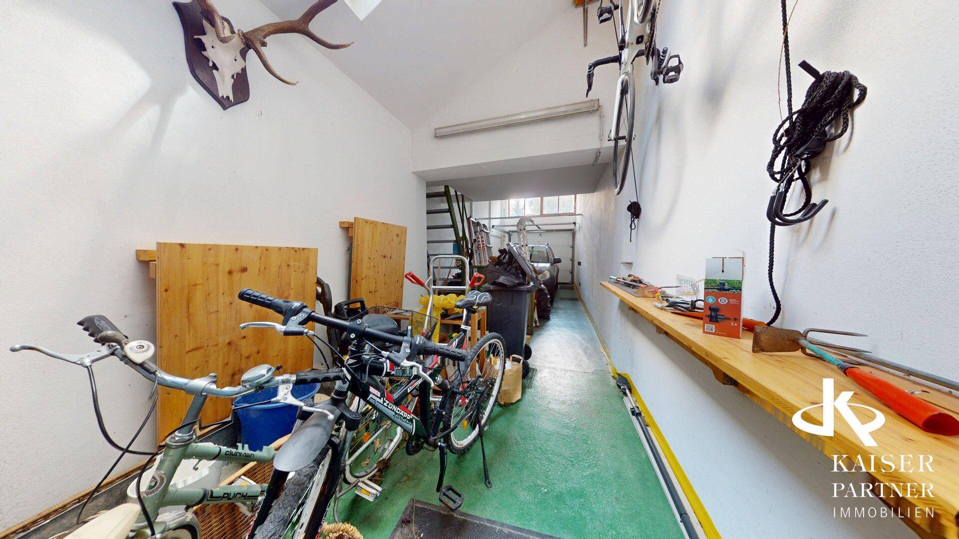 Geräumige Garage mit Abstellmöglichkeiten für Fahrräder und Werkzeuge.