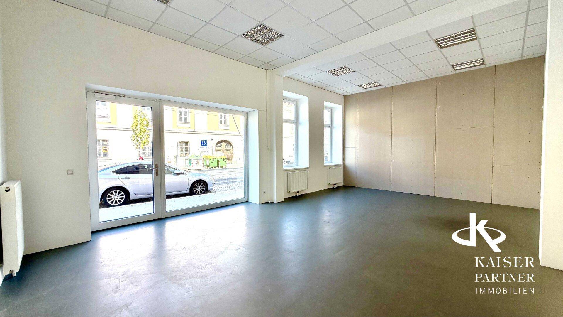 Geräumiger, leerer Geschäftsraum mit großen Fenstern zur Straße und hellem Boden, bereit zur Gestaltung.