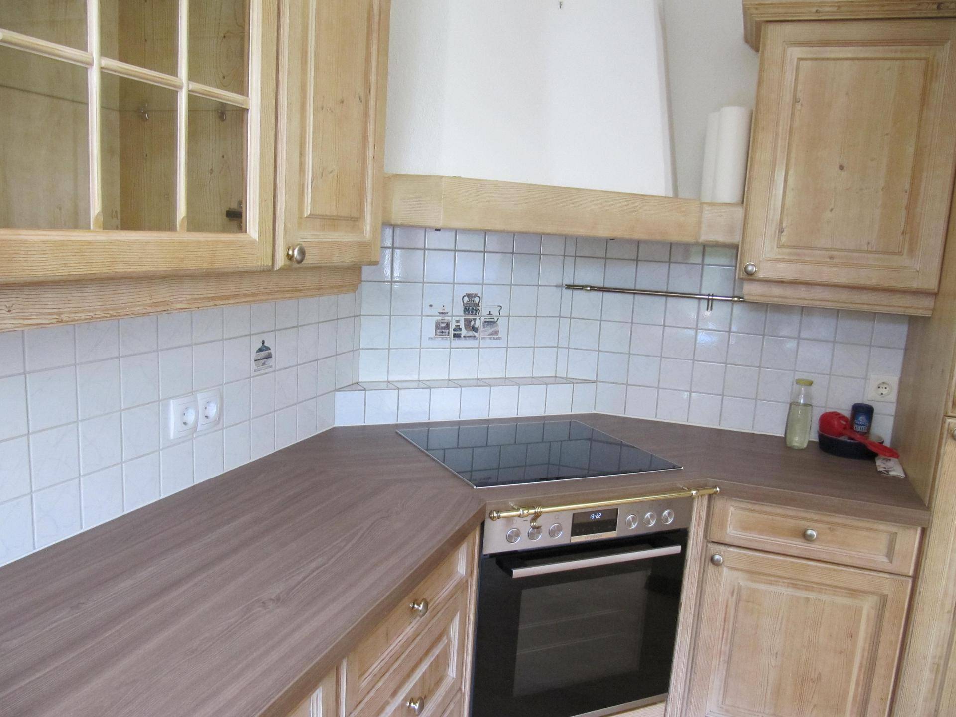 Funktionale Küche mit Induktionskochfeld, Backofen und Holzschränken, ideal für den täglichen Gebrauch.