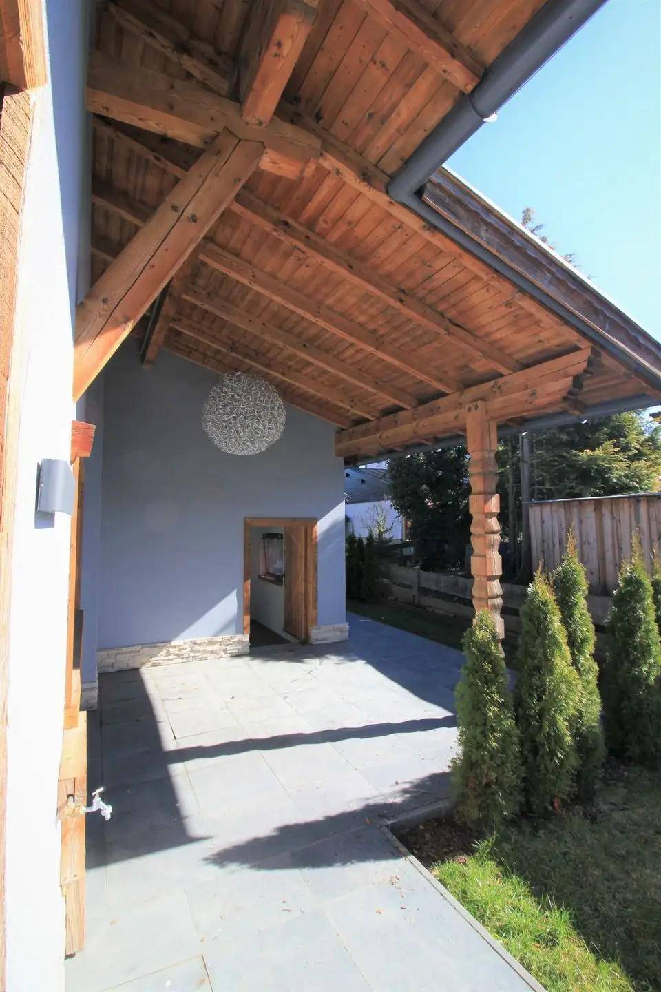 Überdachter Eingangsbereich mit Holzbalken und moderner Deckenleuchte.