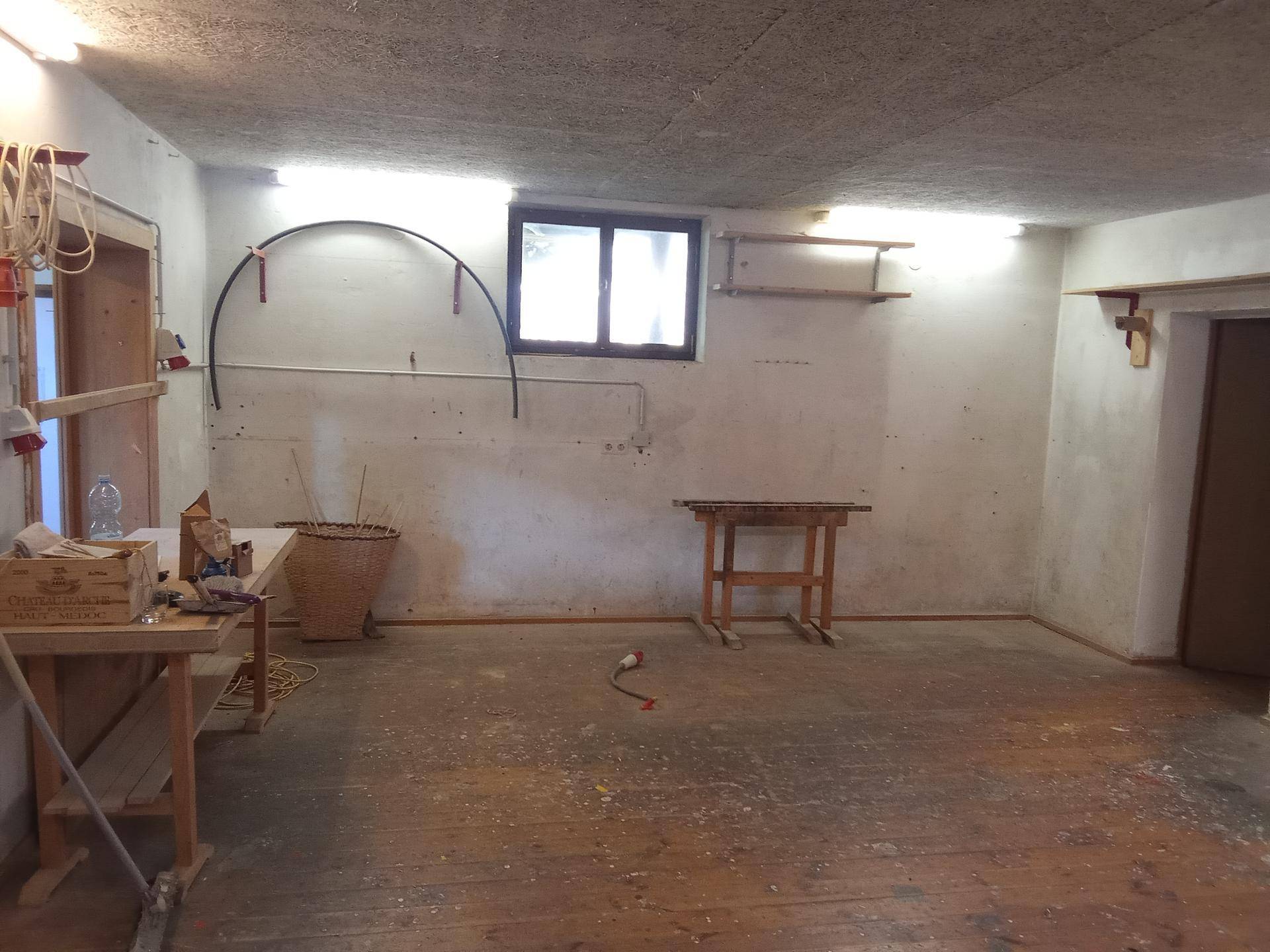 Unfertiger Kellerraum mit Fenster und einfacher Ausstattung, nutzbar als Werkstatt.