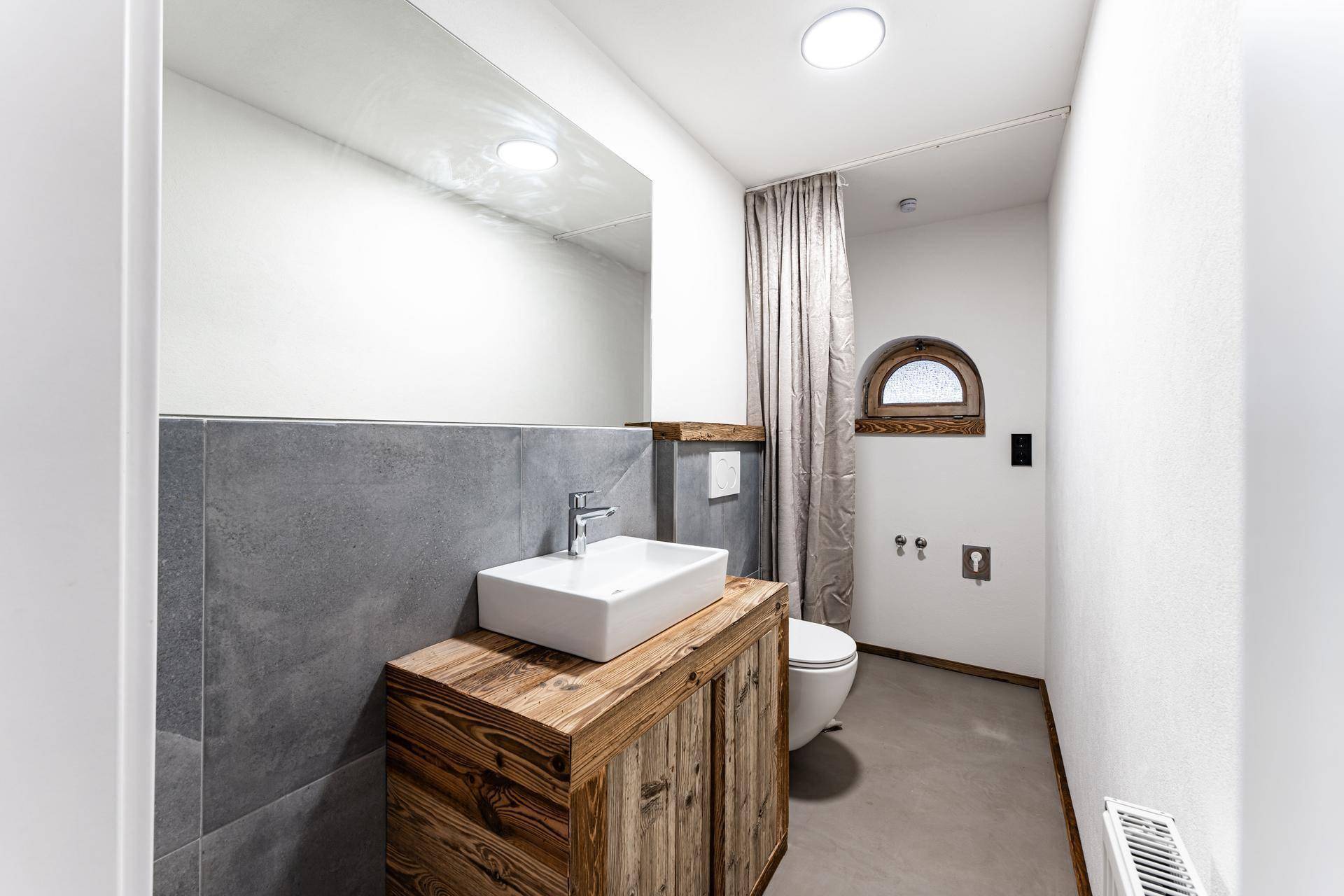 Modernes Badezimmer mit Holzwaschtisch, Aufsatzwaschbecken und kleinem Fenster.