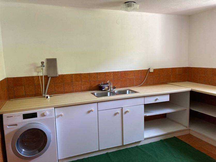 Praktischer Hauswirtschaftsraum mit Waschmaschine, Doppelspüle und Ablageflächen.