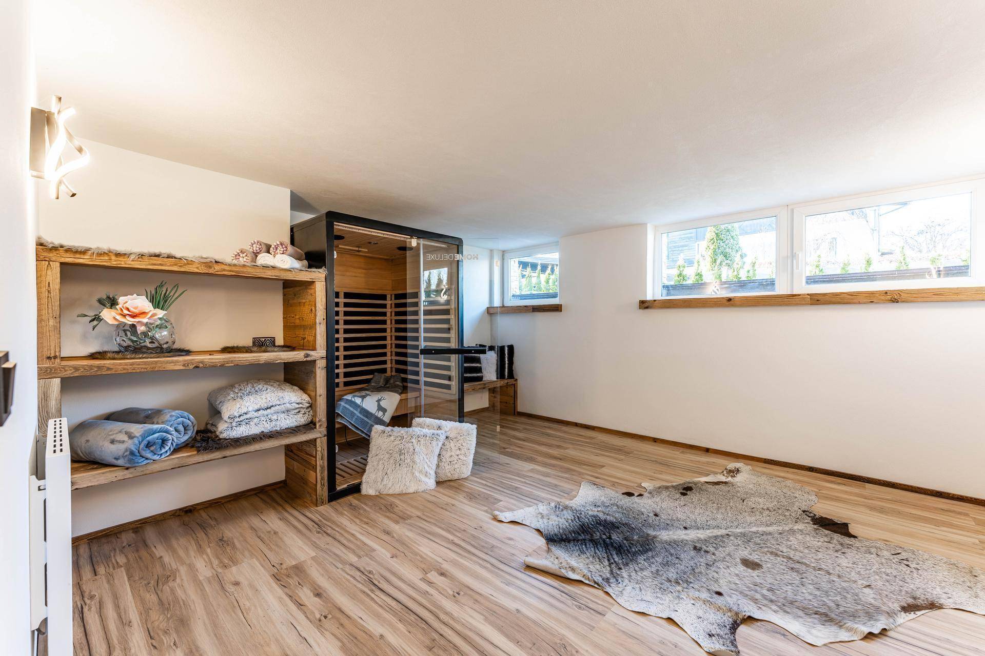 Wellnessbereich im Untergeschoss mit Sauna, Regalen und großem Fenster.