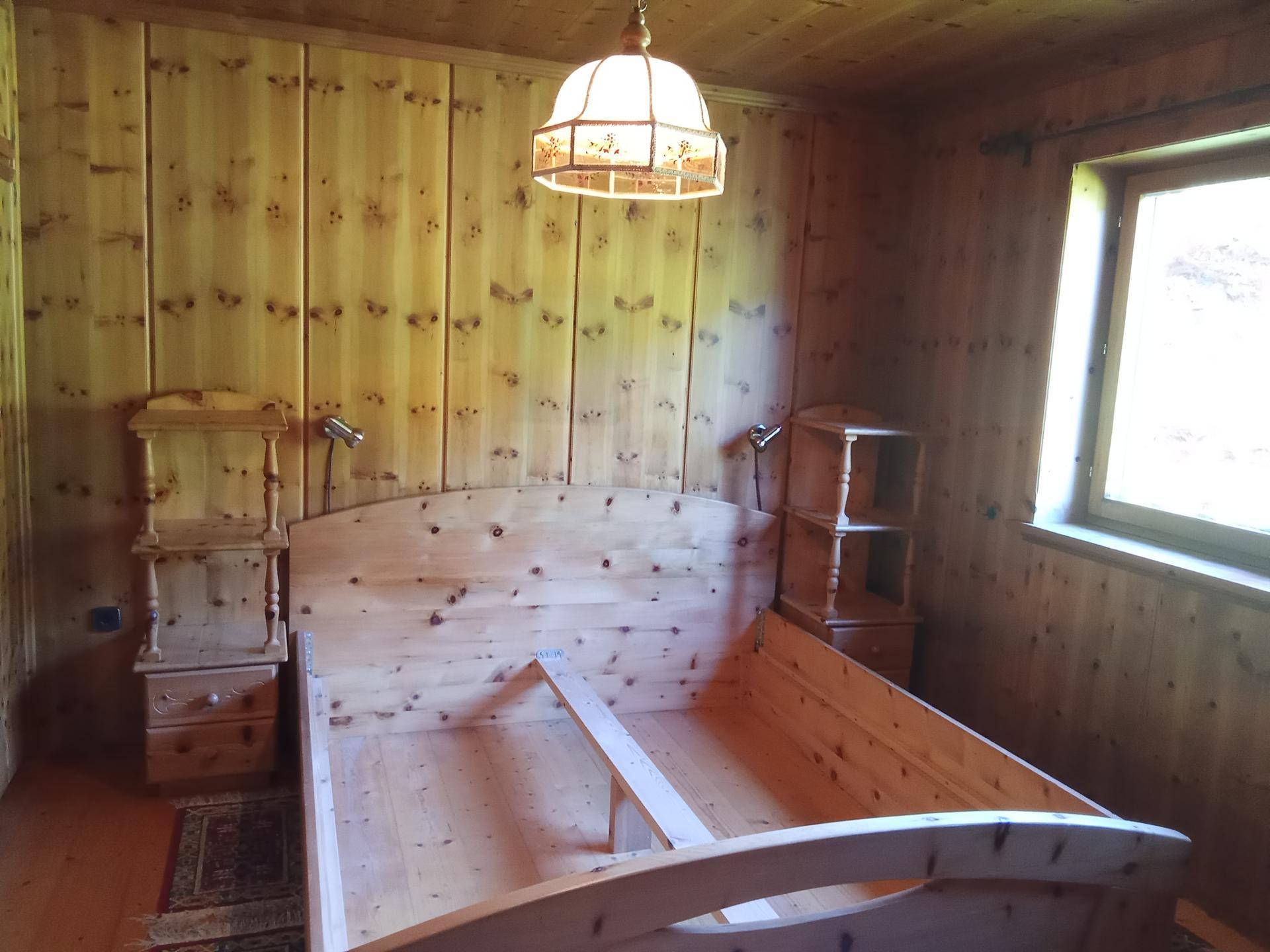 Schlafzimmer im Landhausstil mit heller Holztäfelung und traditionellem Bettrahmen.