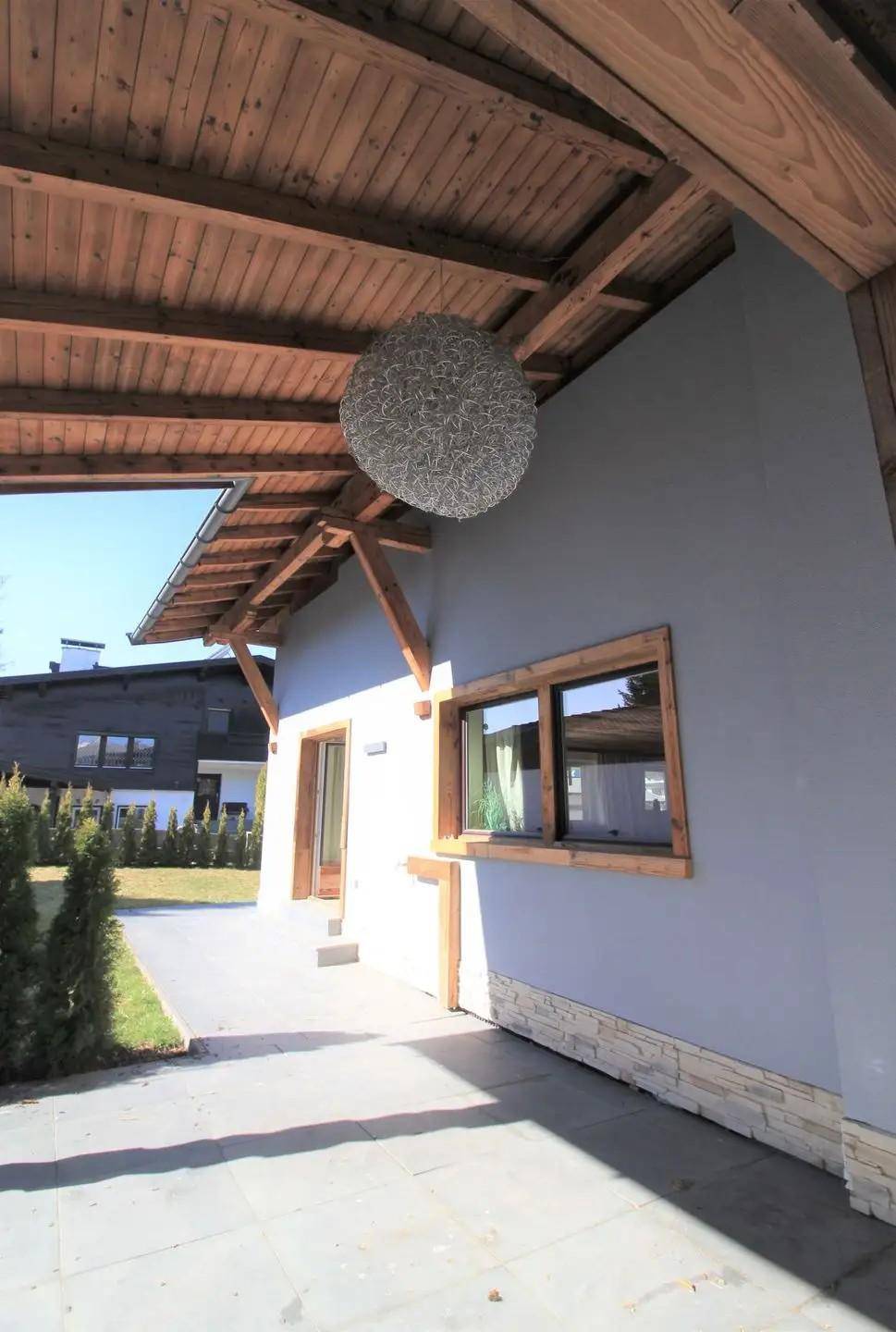 Überdachte Terrasse mit Holzdach und Blick auf die Umgebung.