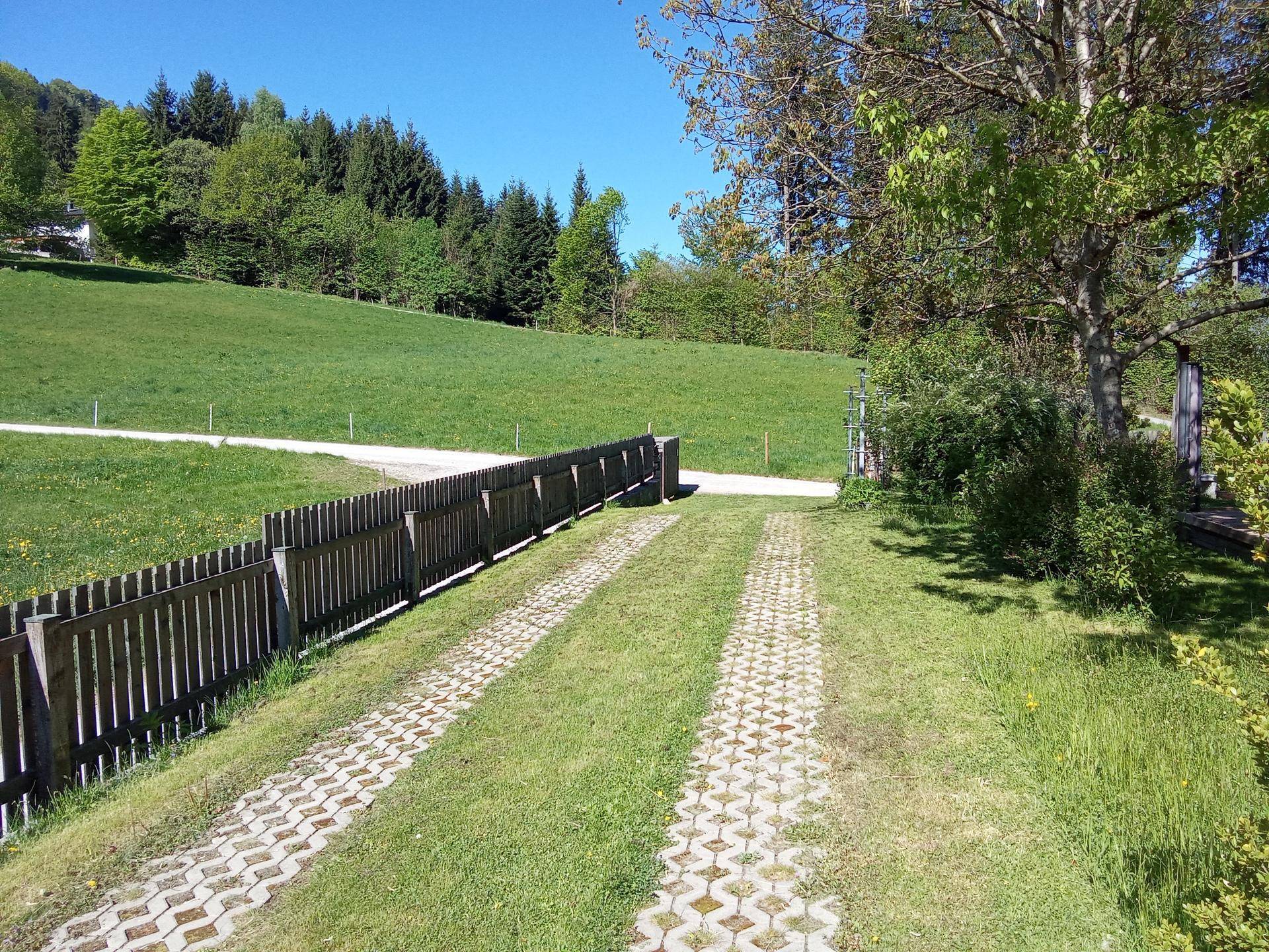 Zufahrt zum Anwesen mit gepflastertem Weg und Blick auf die umliegenden grünen Hügel.