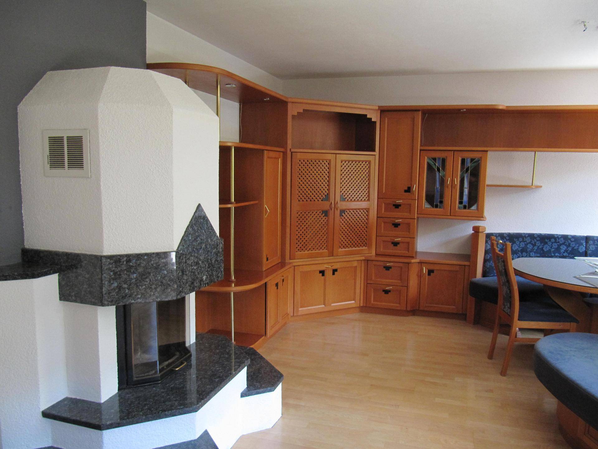 Wohnbereich mit traditionellem Kamin, Holzeinbauten und Parkettboden, der eine warme Atmosphäre schafft.