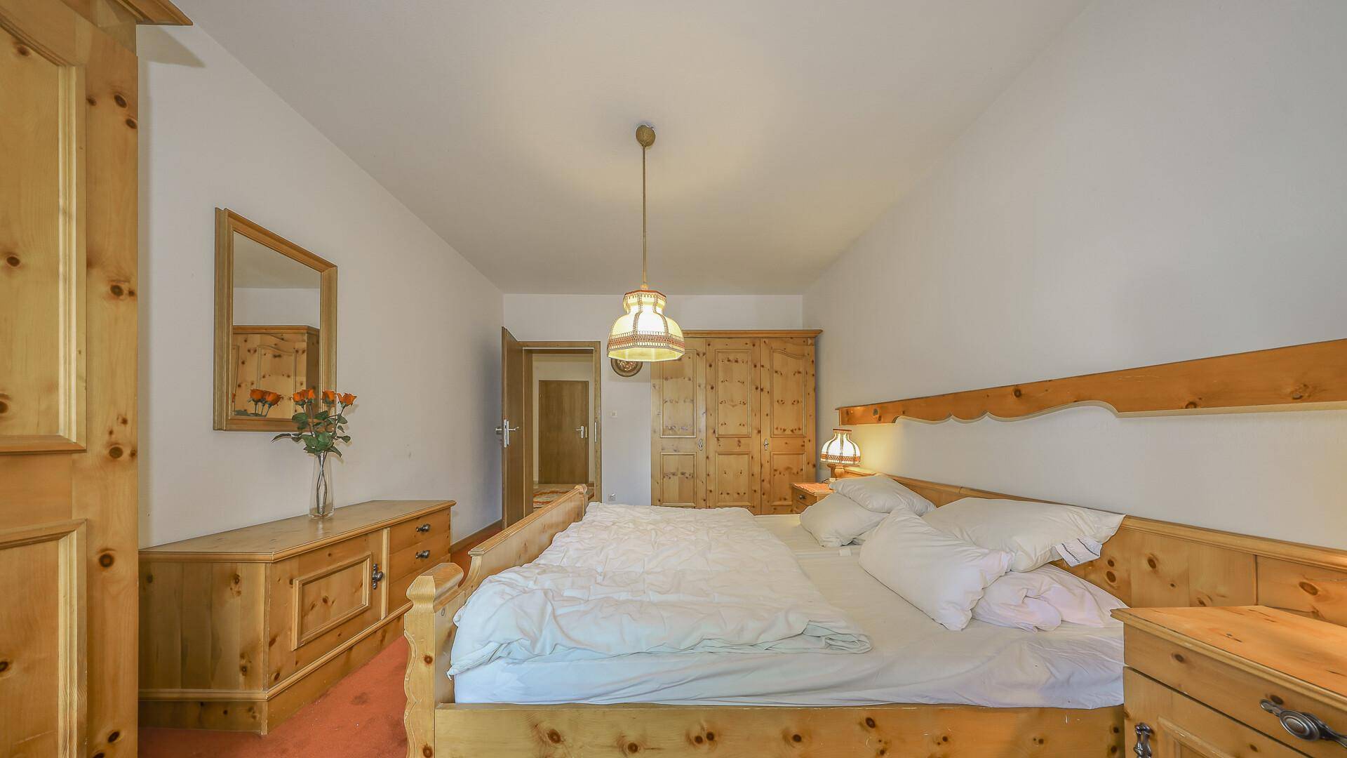 Gemütliches Schlafzimmer mit traditionellen Holzmöbeln, Teppichboden und Kleiderschrank.