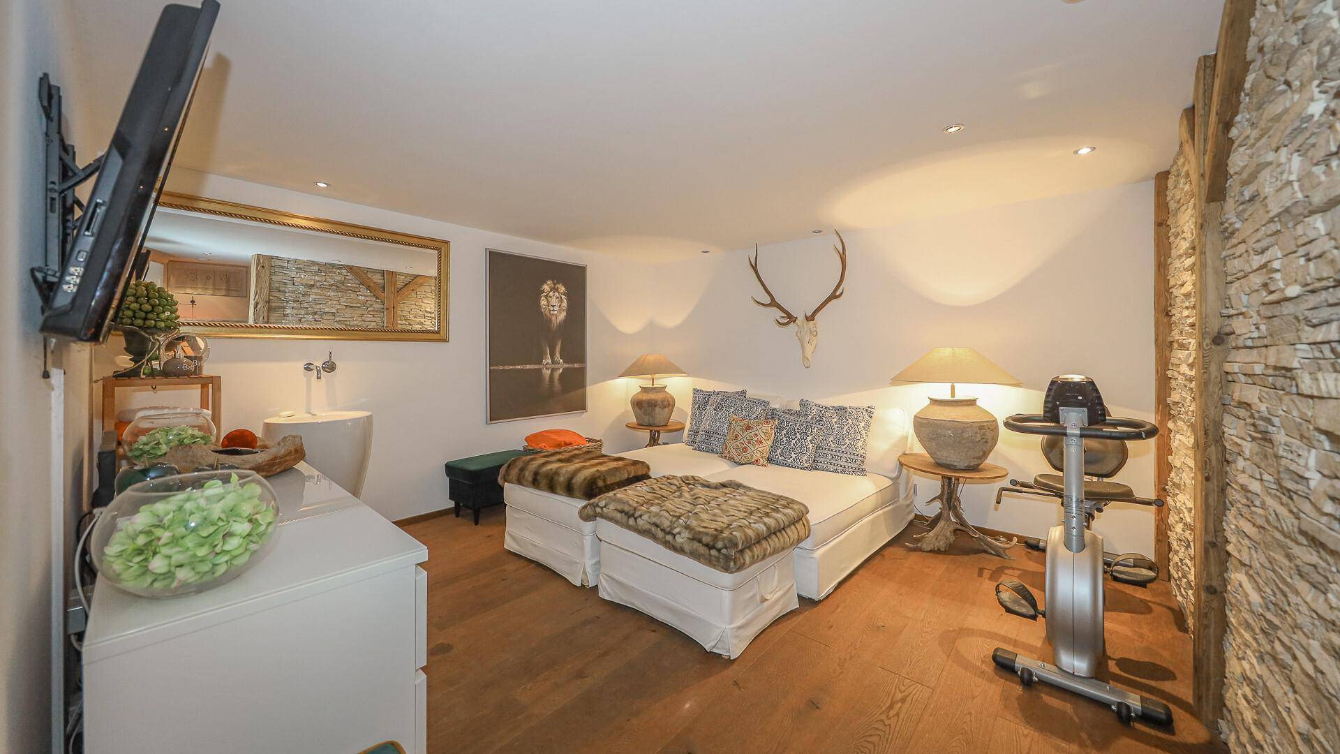 Gemütliches Schlafzimmer mit Holzboden, Steinwand und Fitnessgerät für aktive Erholung.