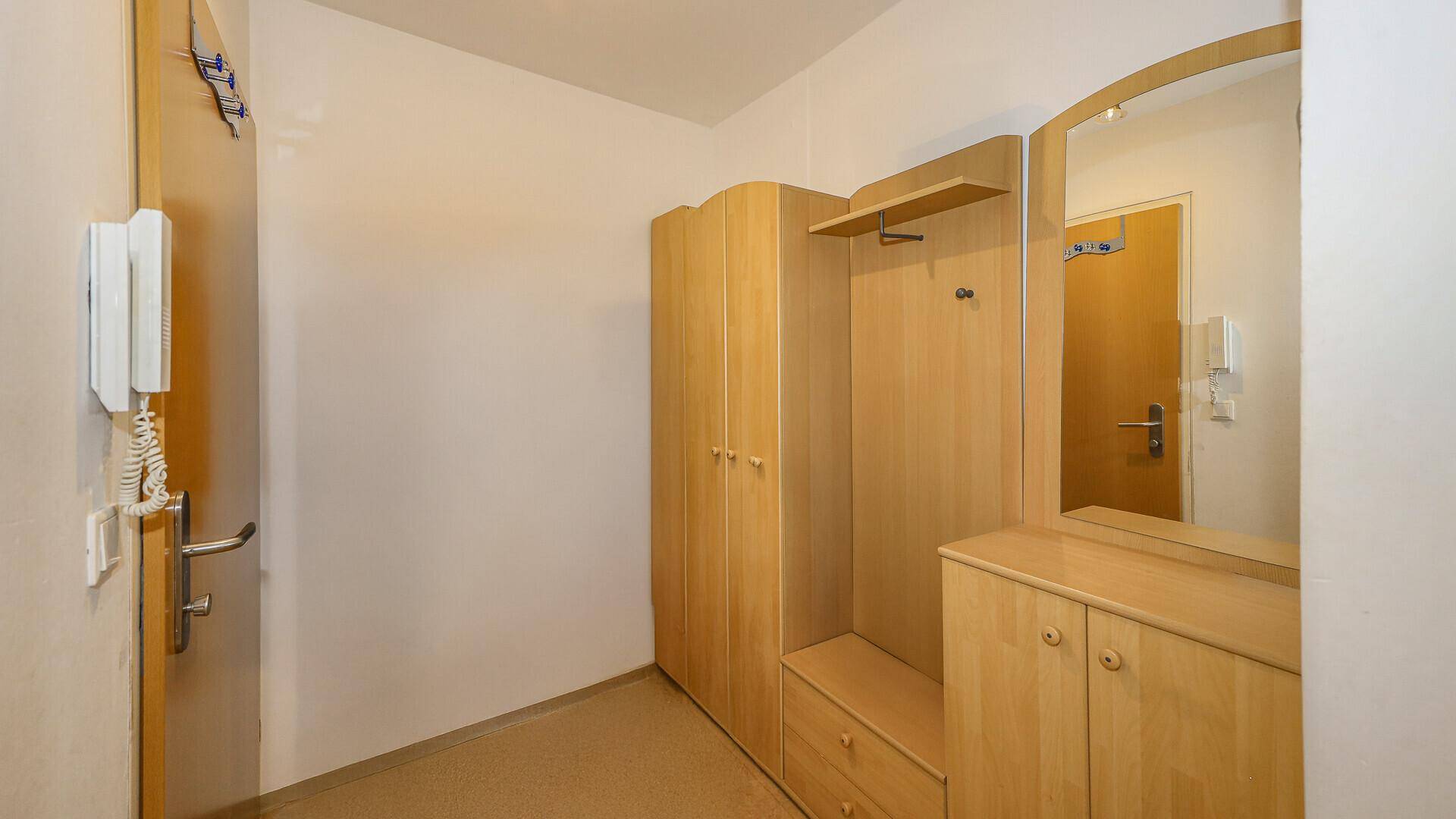 Eingangsbereich mit Garderobe, Holzschrank und Spiegel, bietet praktischen Stauraum.