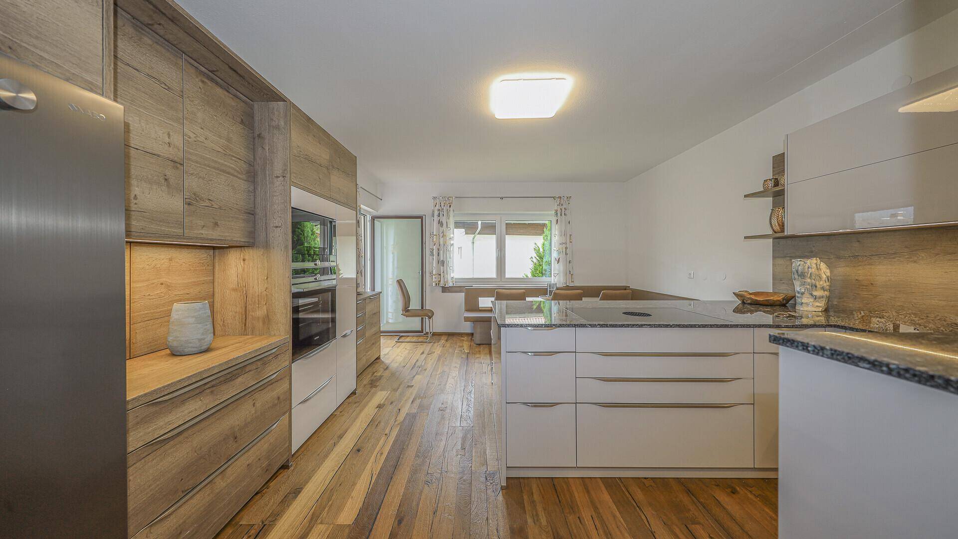 Helle Küche mit Holzboden, weißen Schränken und Granitarbeitsplatte.