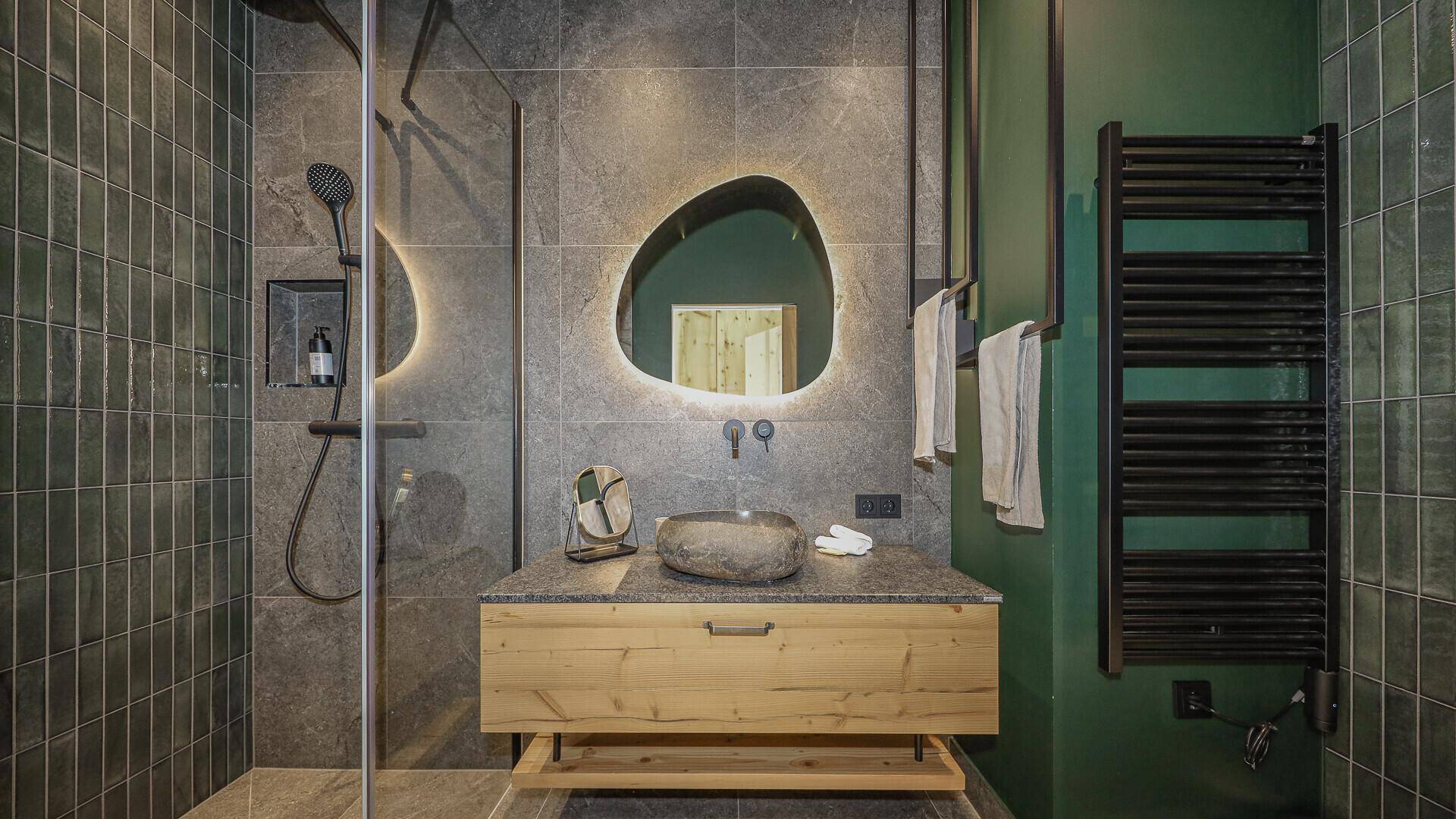 Stilvolles Badezimmer mit grauen Fliesen, einzigartigem Spiegel und Natursteinwaschbecken.