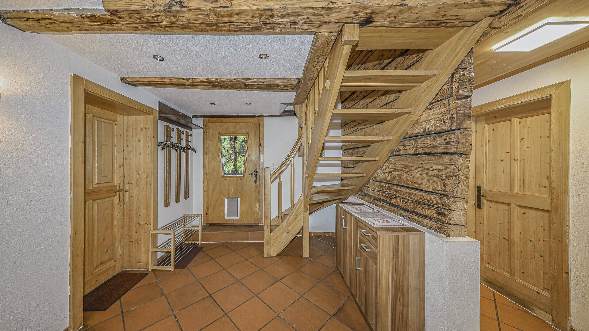 Eingangsbereich mit Holztreppe, Garderobe und Terrakotta-Fliesenboden, im traditionellen Stil.